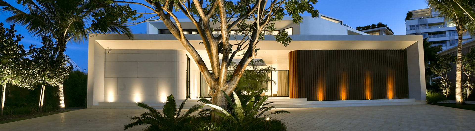 exterior of modern house with landscape accent lights shining on house and uplighting landscaping