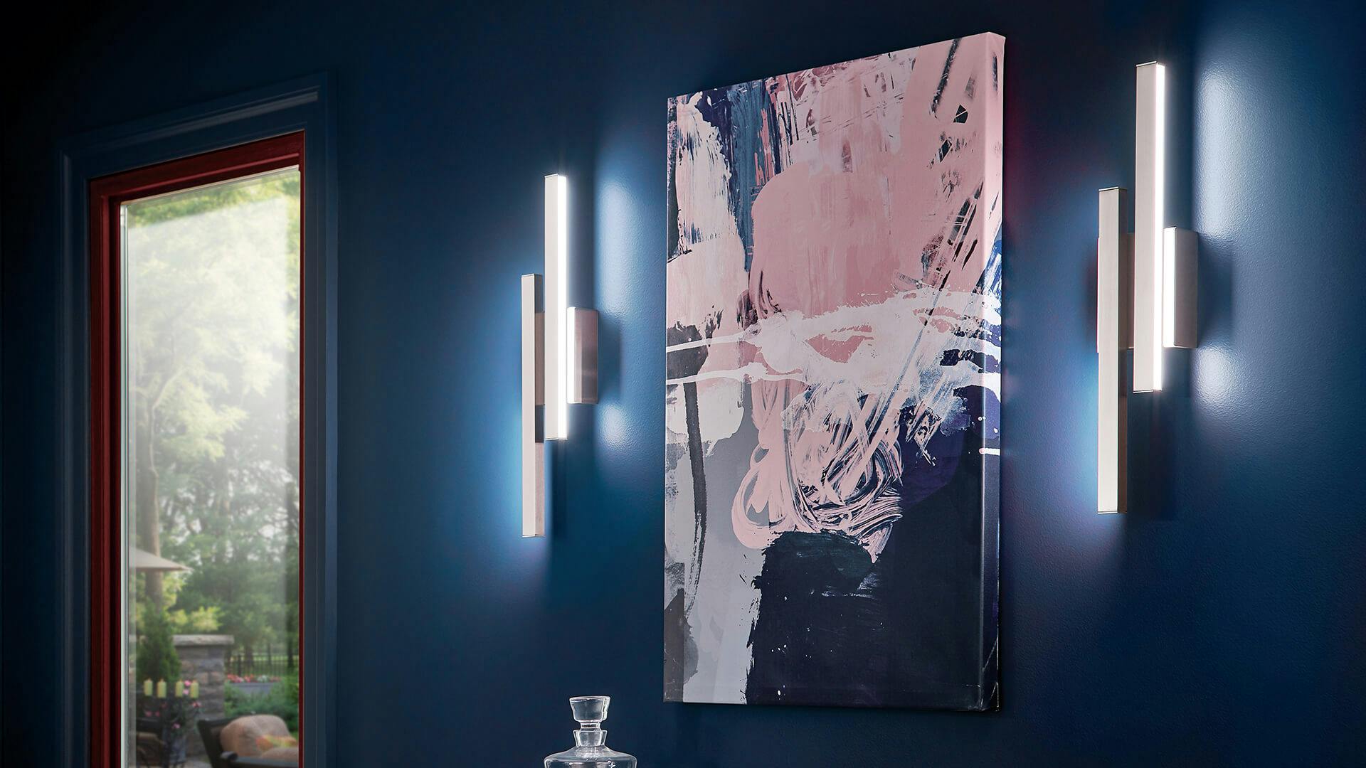 A blue wall with an abstract painting of pink, white, and dark purples with Idril sconce lights on either side