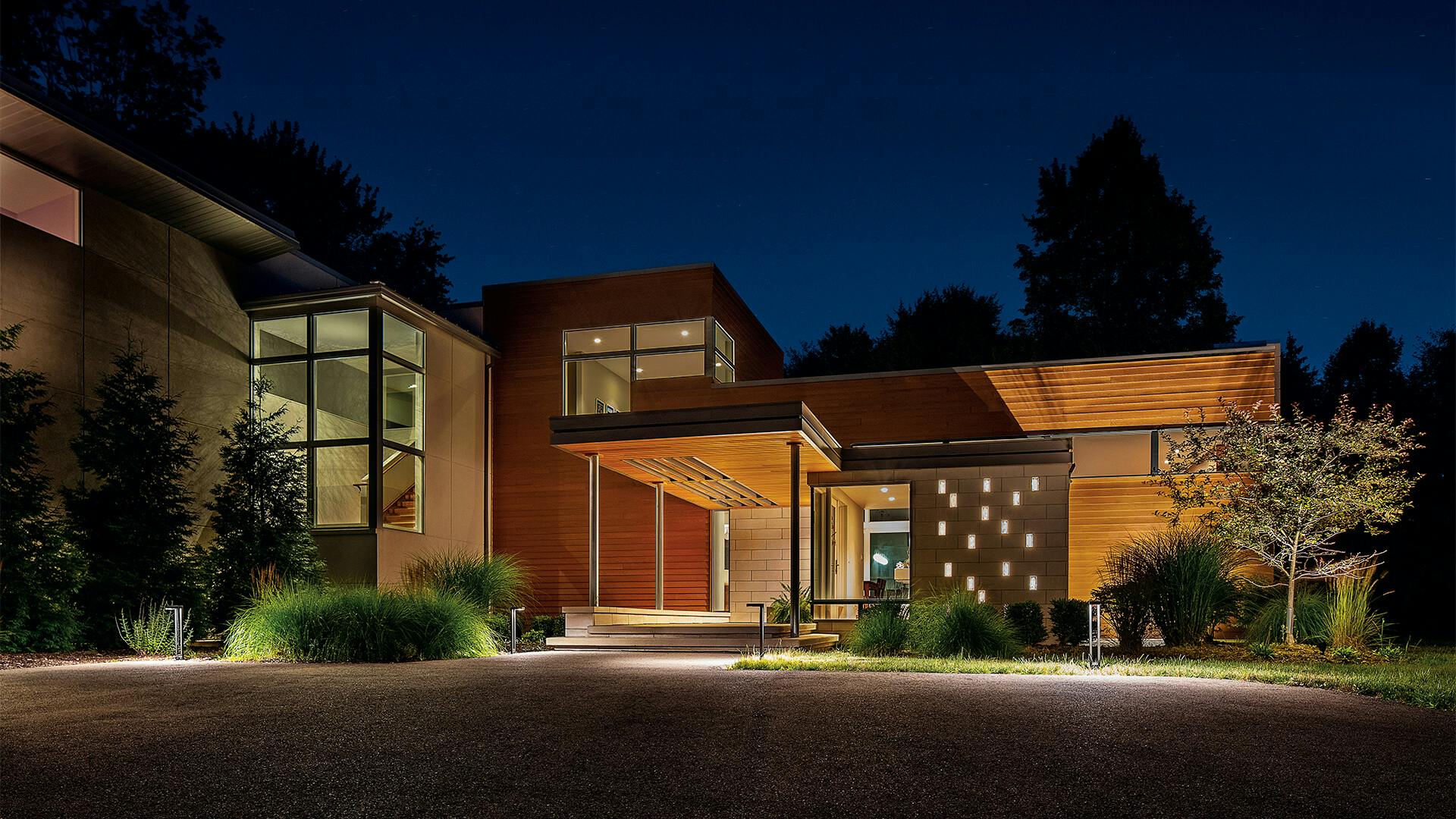 Contemporary residential home at night with variety of landscape lighting