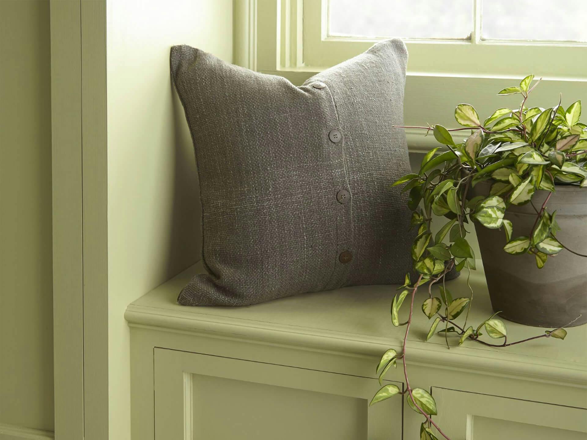 Bay window bench seat with pillow and potted plant.