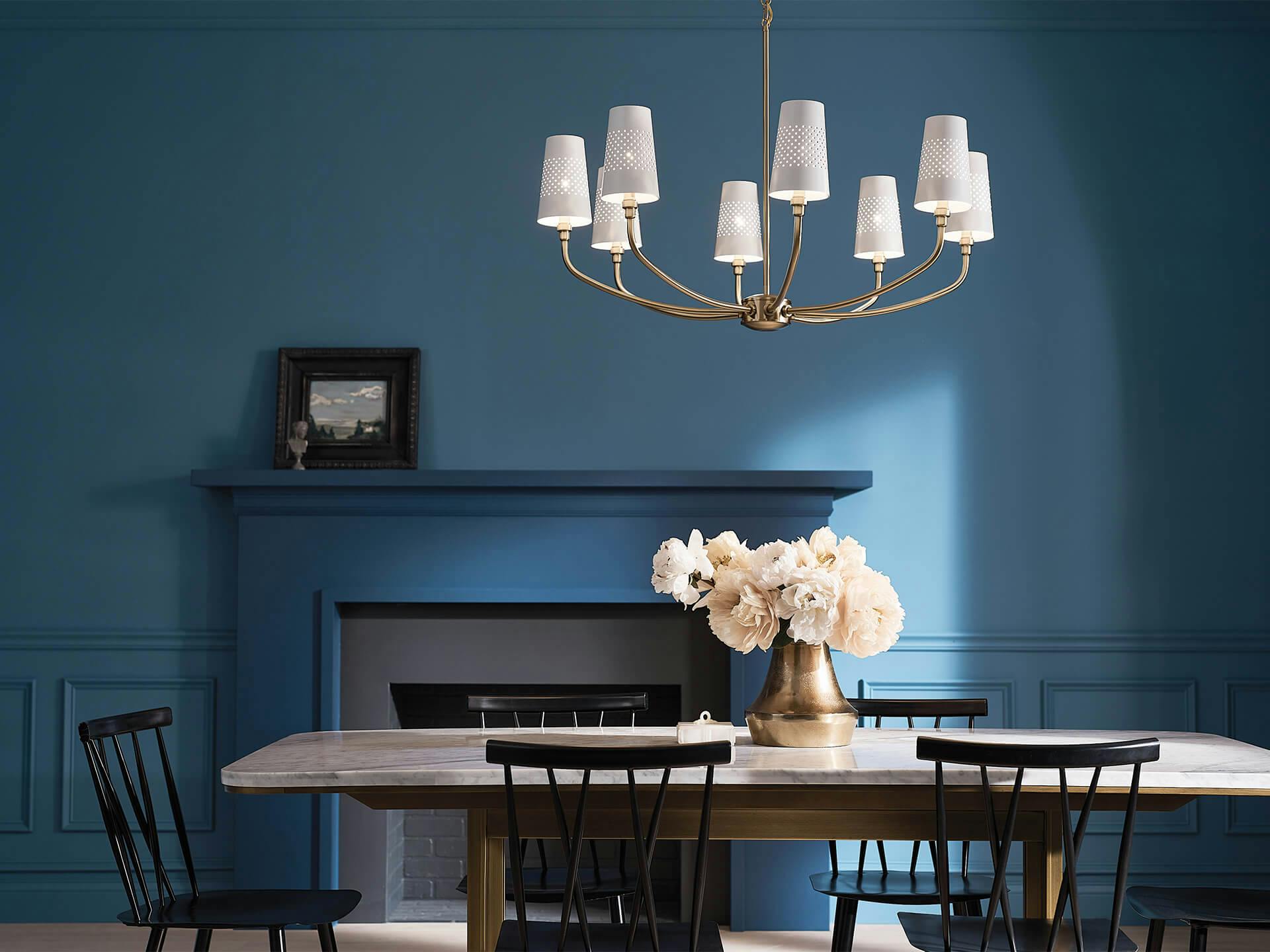 Blue dining room with table and fireplace with an Adeena 8-light Chandelier in brushed natural brash and white finish