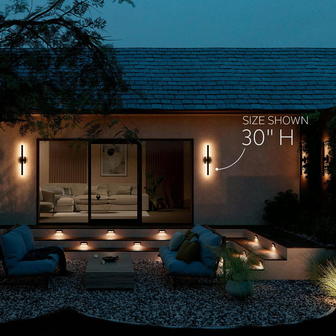 Patio at night with the Nocar 30" LED Outdoor Wall Light in Textured Black