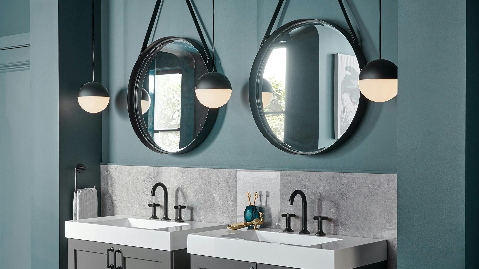Daylit bathroom with two sinks, each with a mirror above them and a glowing Moonlit hanging light on each side