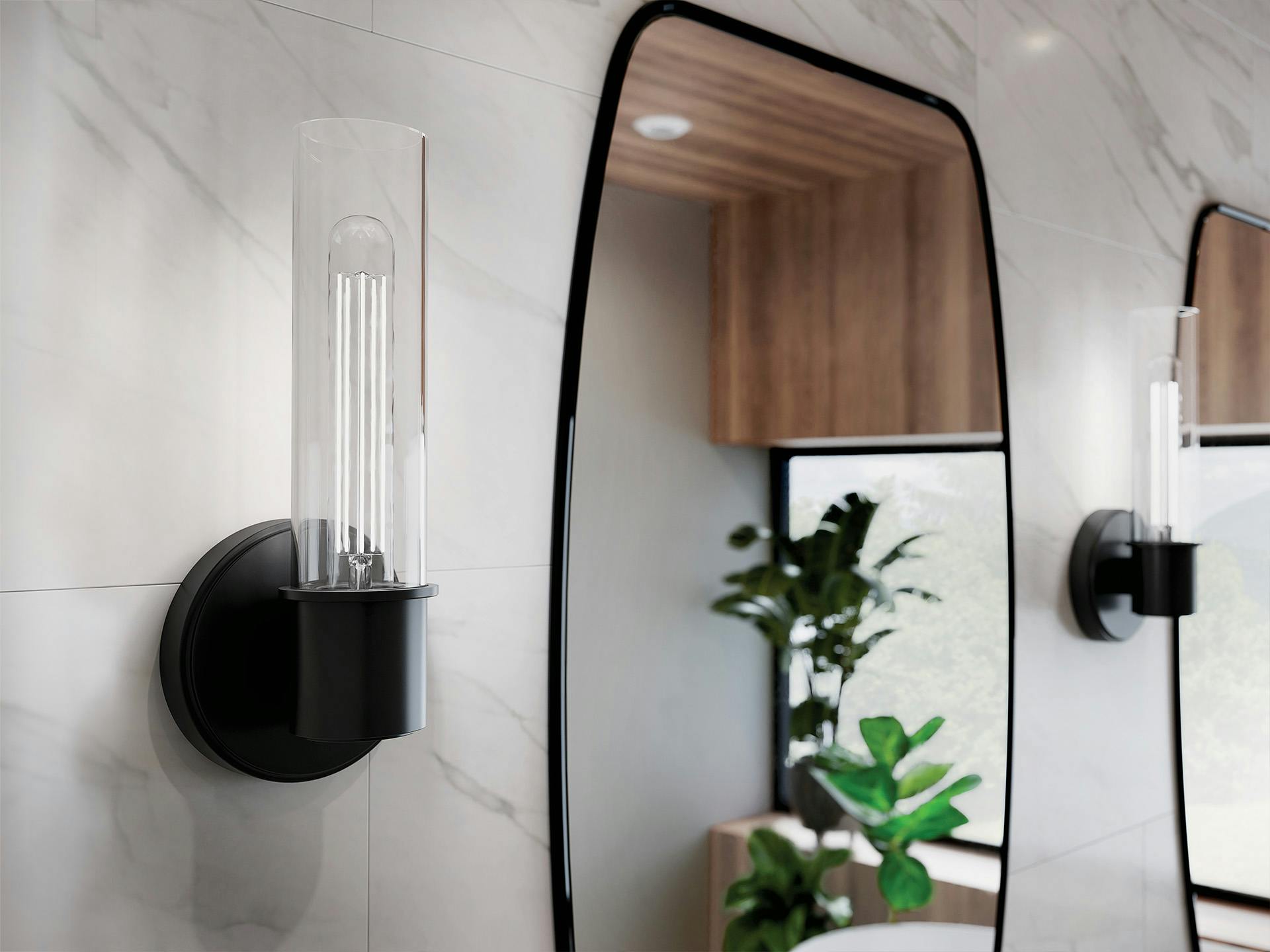 Aviv wall sconce in black finish on a white tiled wall next to a black framed mirror