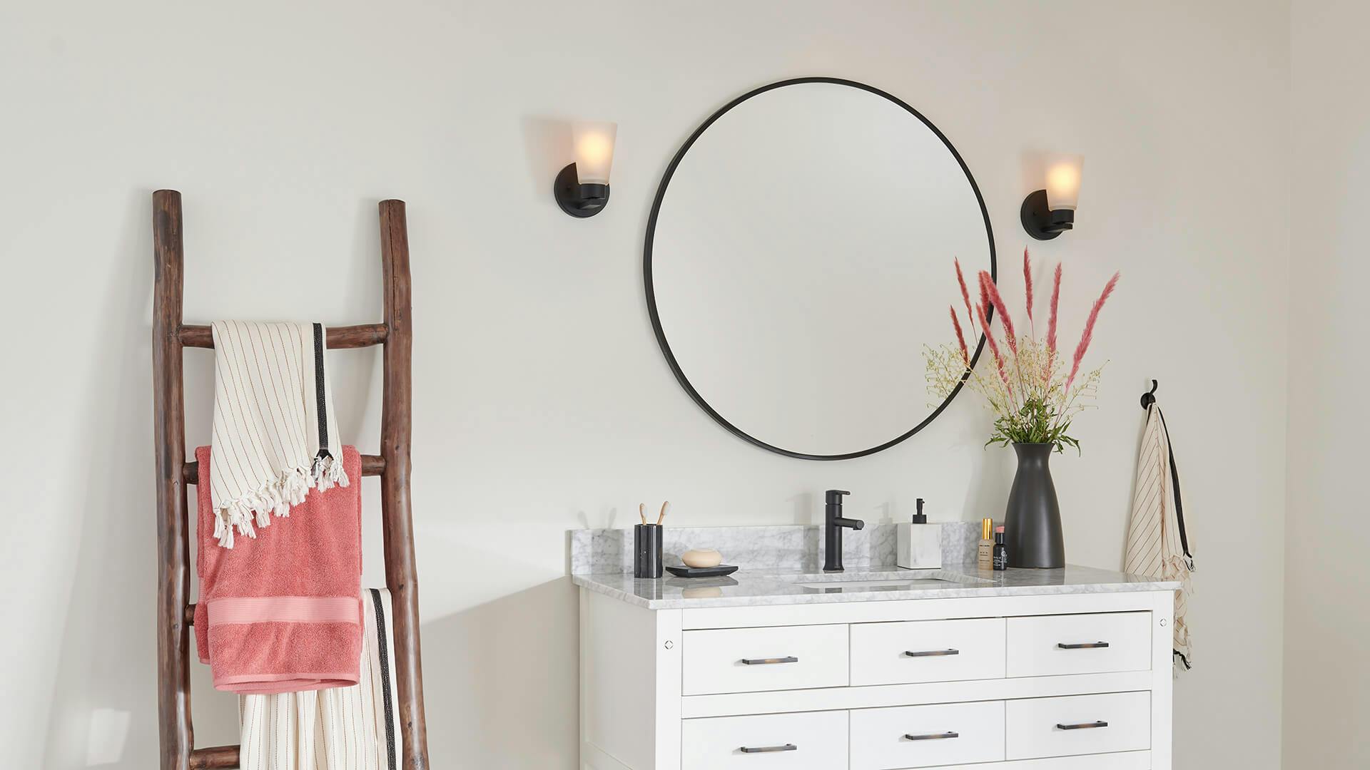 Contemporary bathroom with ladder rack for towels and round mirror vanity, featuring two Stamos sconces on either side.