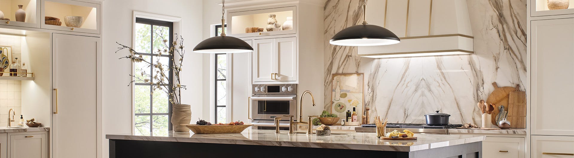 Kitchen with white and black cabinets and marble countertops with two delarosa pendants hanging over center island