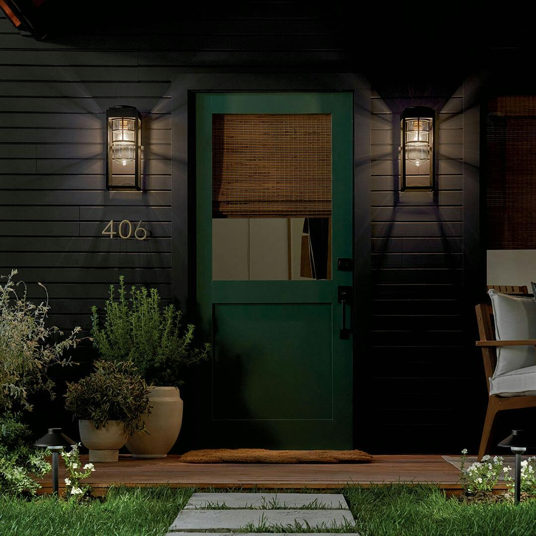 Patio at dusk with the Hone 18" 1 Light Outdoor Wall Light with Clear Glass in Textured Black with Natural Brass Accent