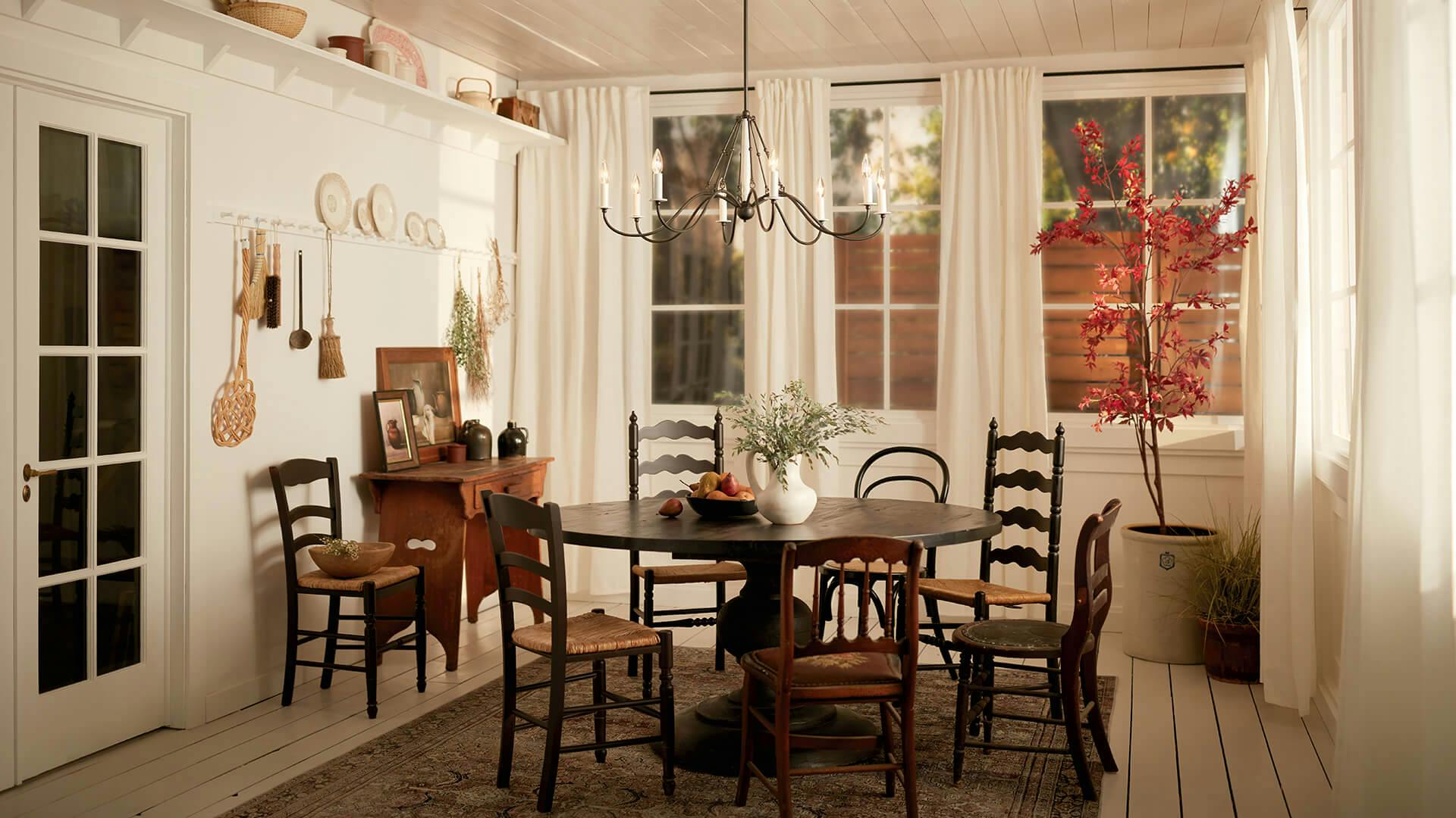 Rustic dining room, white walls with a black table with ladderback chairs featuring a Freesia chandelier