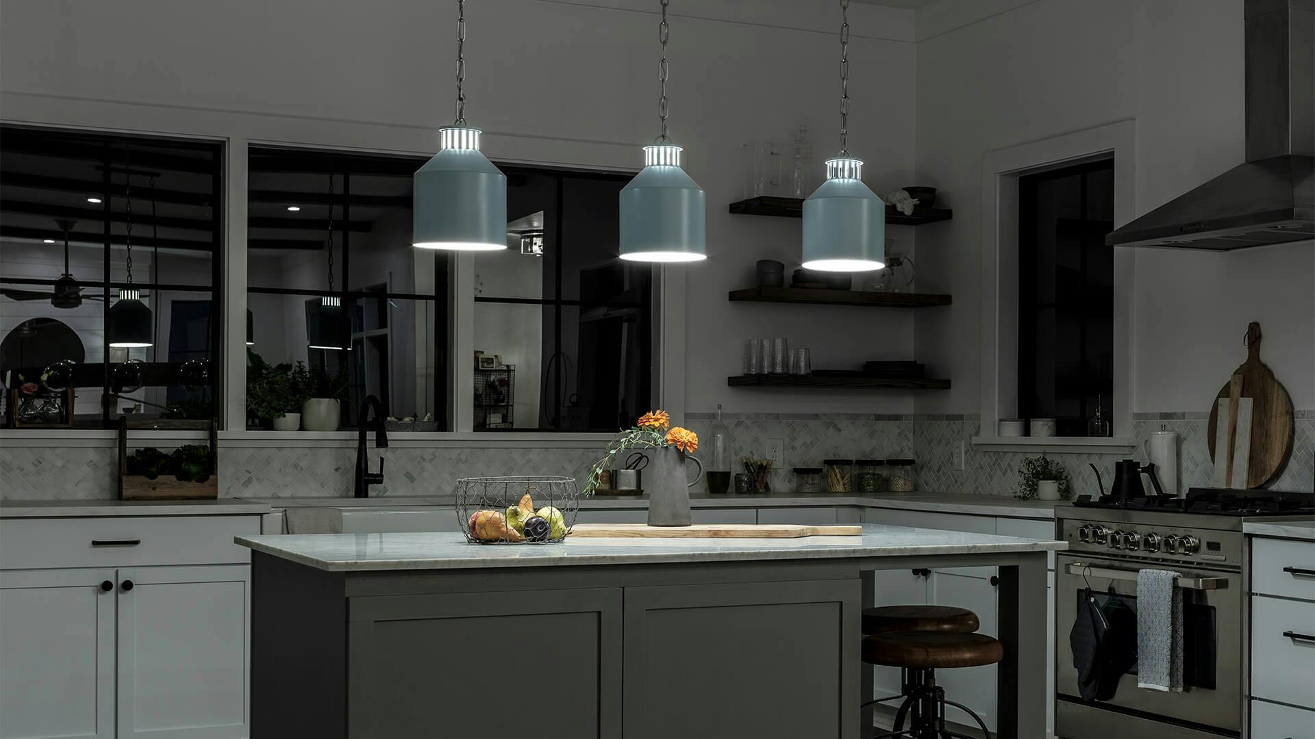 A dimly lit kitchen with three pendants glowing above the island