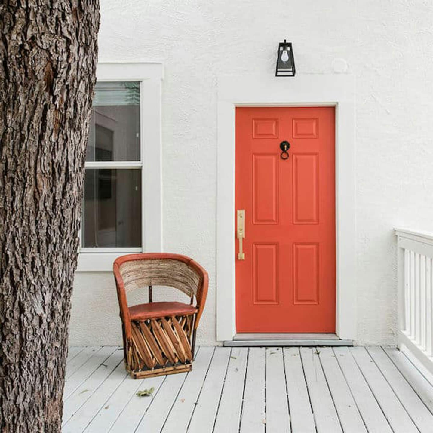 Exterior image of a front porch with white wood paneled flooring, white walls, with a bright red front door