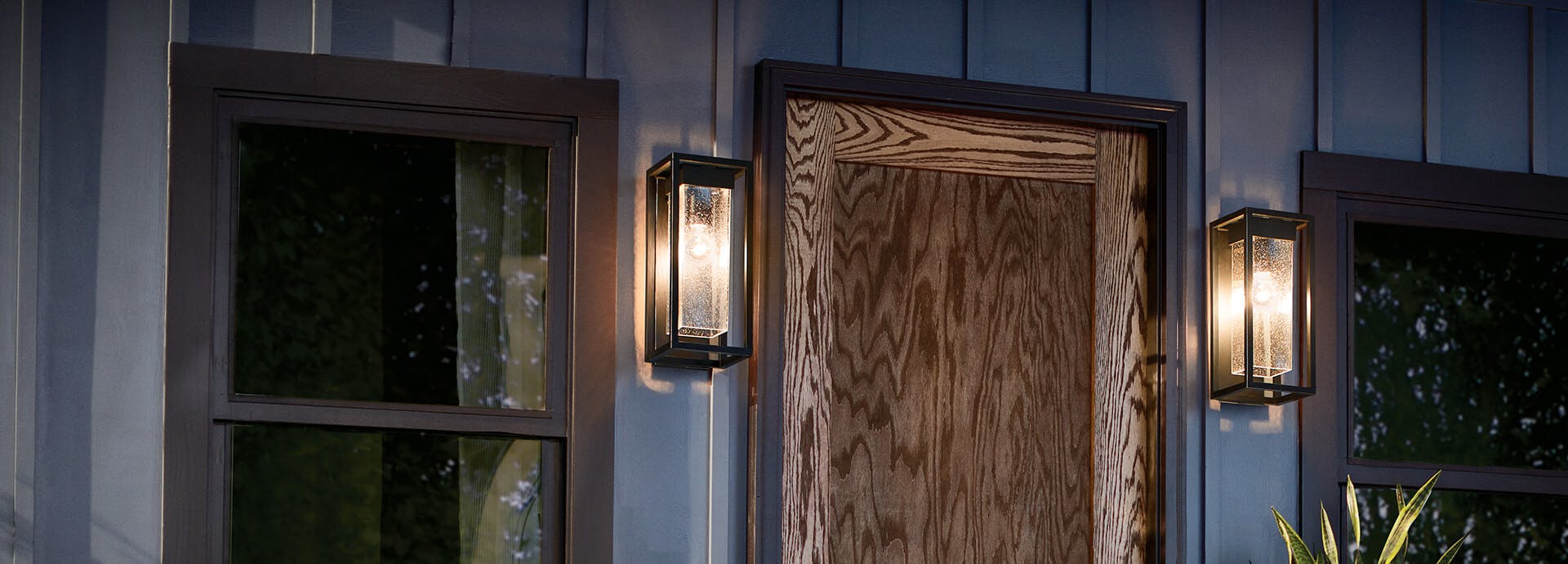 Outdoor patio at night with Mercer sconces on either side of a wooden front door at night