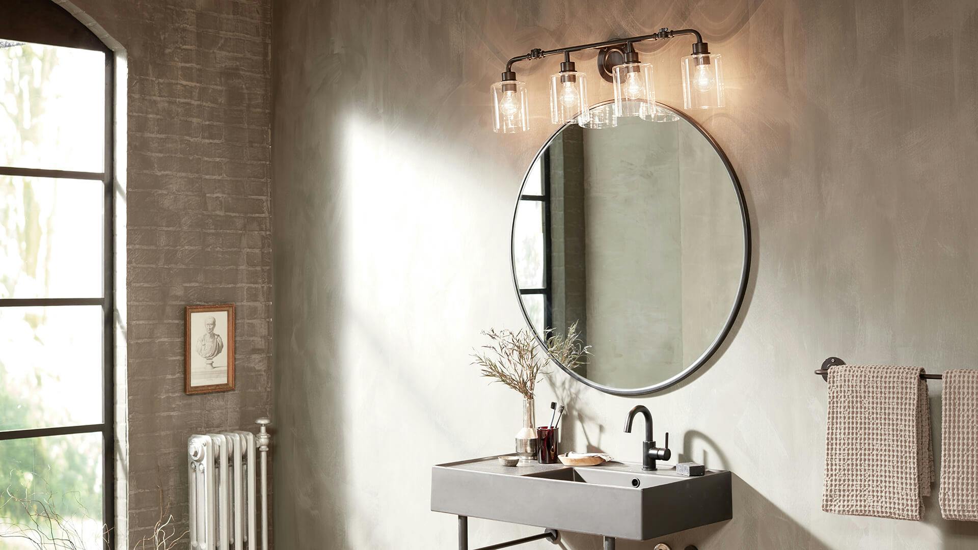 Bathroom with cement walls and floor to ceiling window with light pouring in featuring a Gunnison sconce above a round mirror