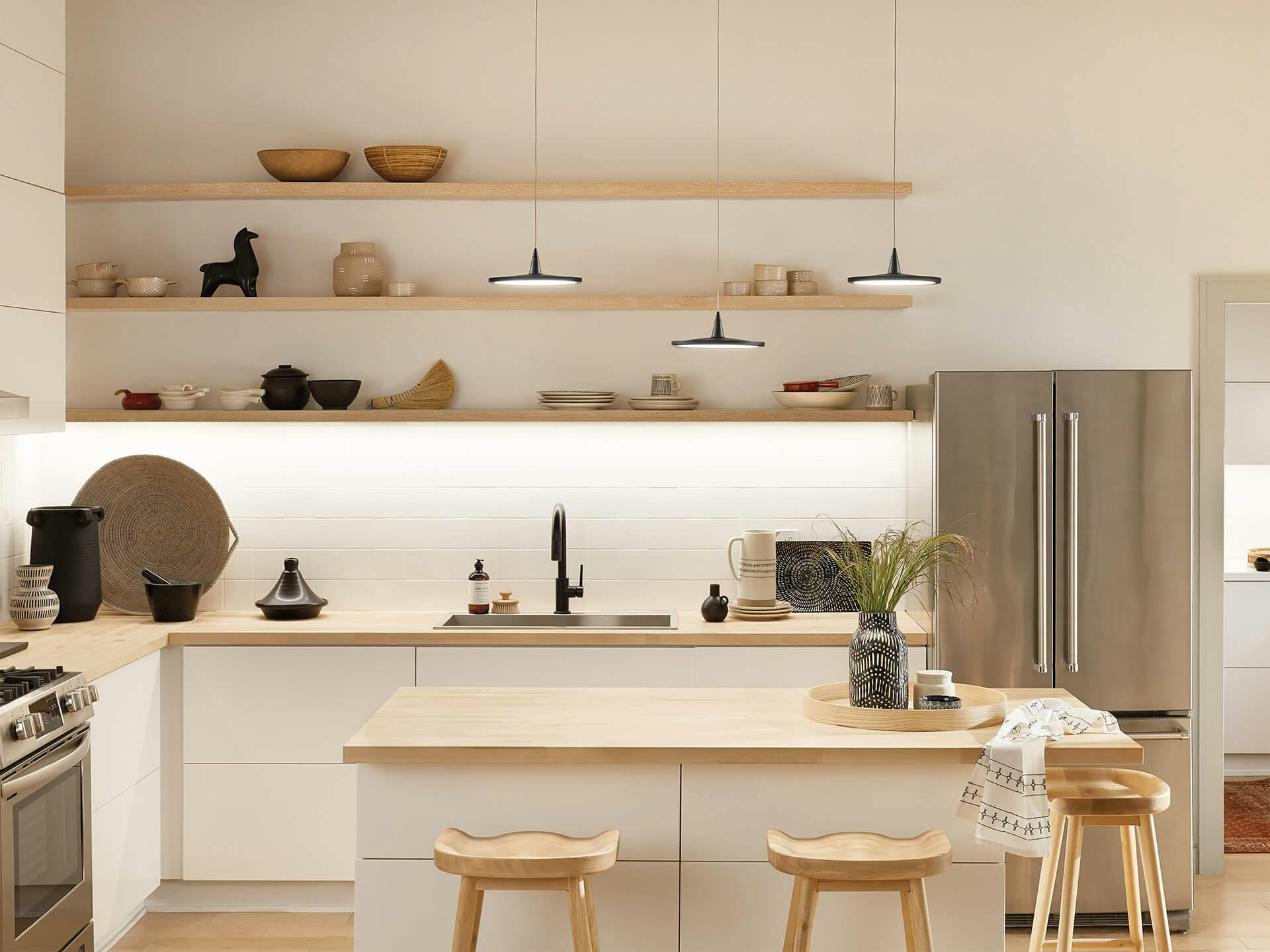 Scandinavian style Kitchen with three Jeno pendants over a wooden kitchen island with tape lights lighting up a shelf on the back wall 
