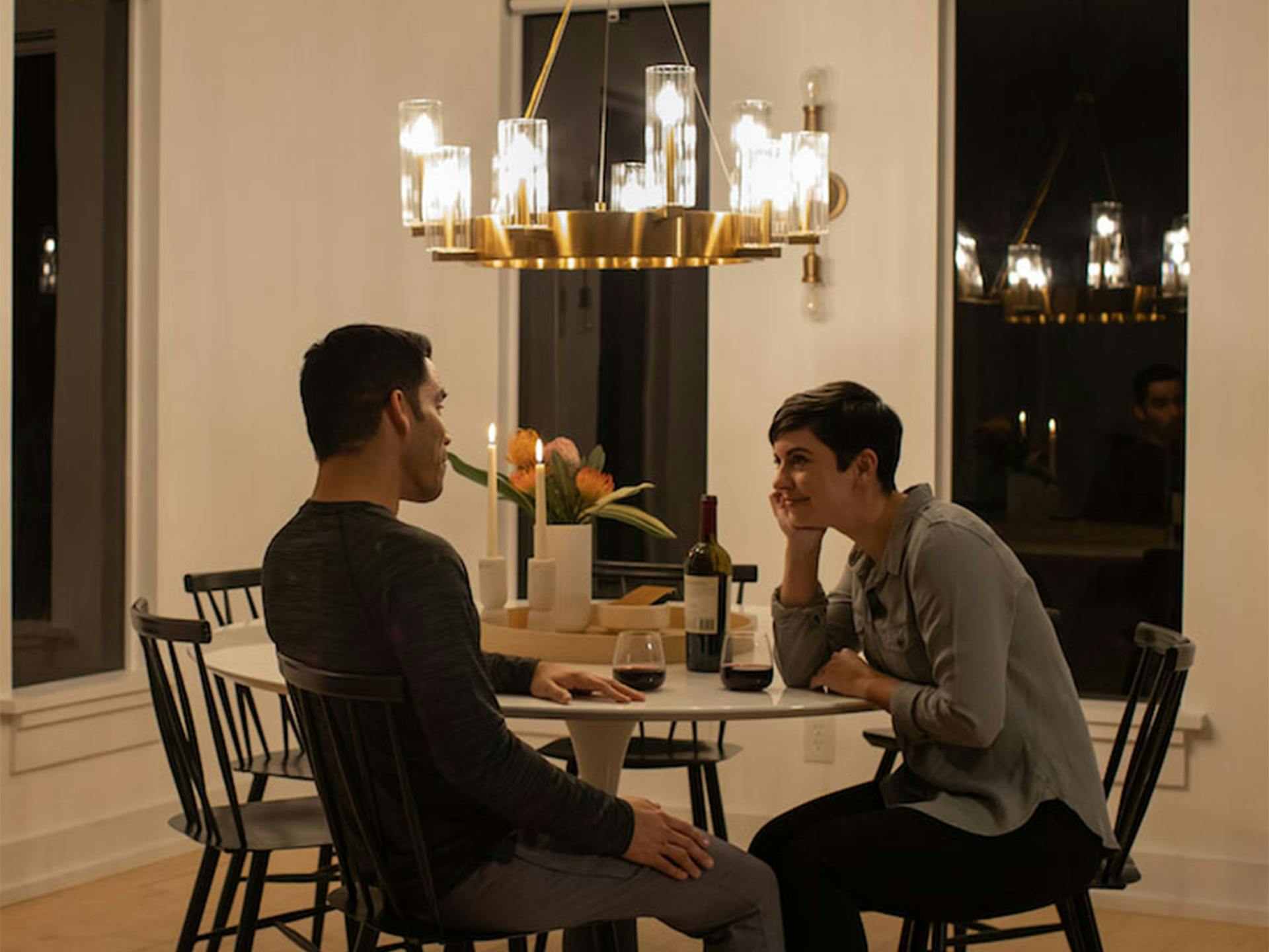 A couple in a dinning room lit with a gold erzo chandelier