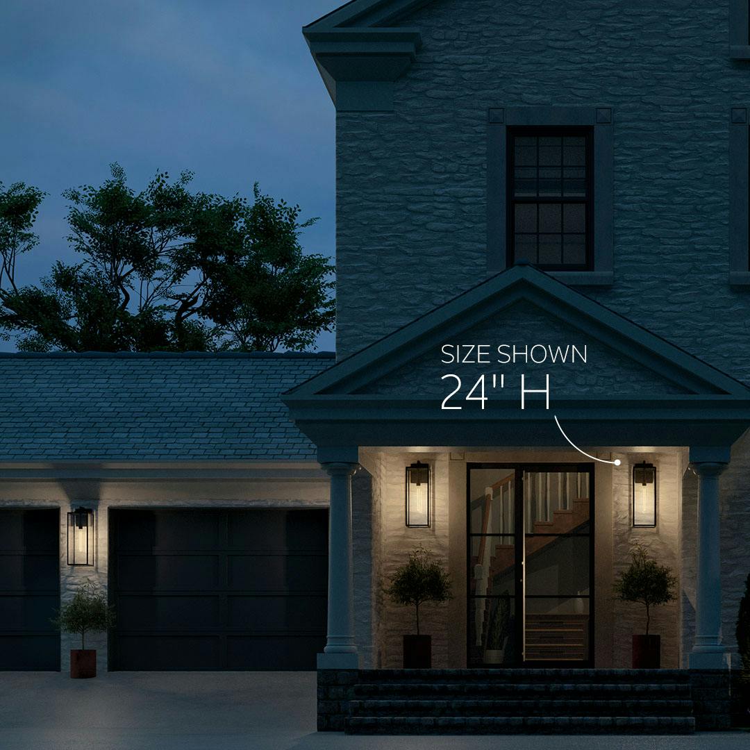Home exterior at night with the Branner 24" 1 Light Outdoor Wall Light with Clear Glass in Textured Black