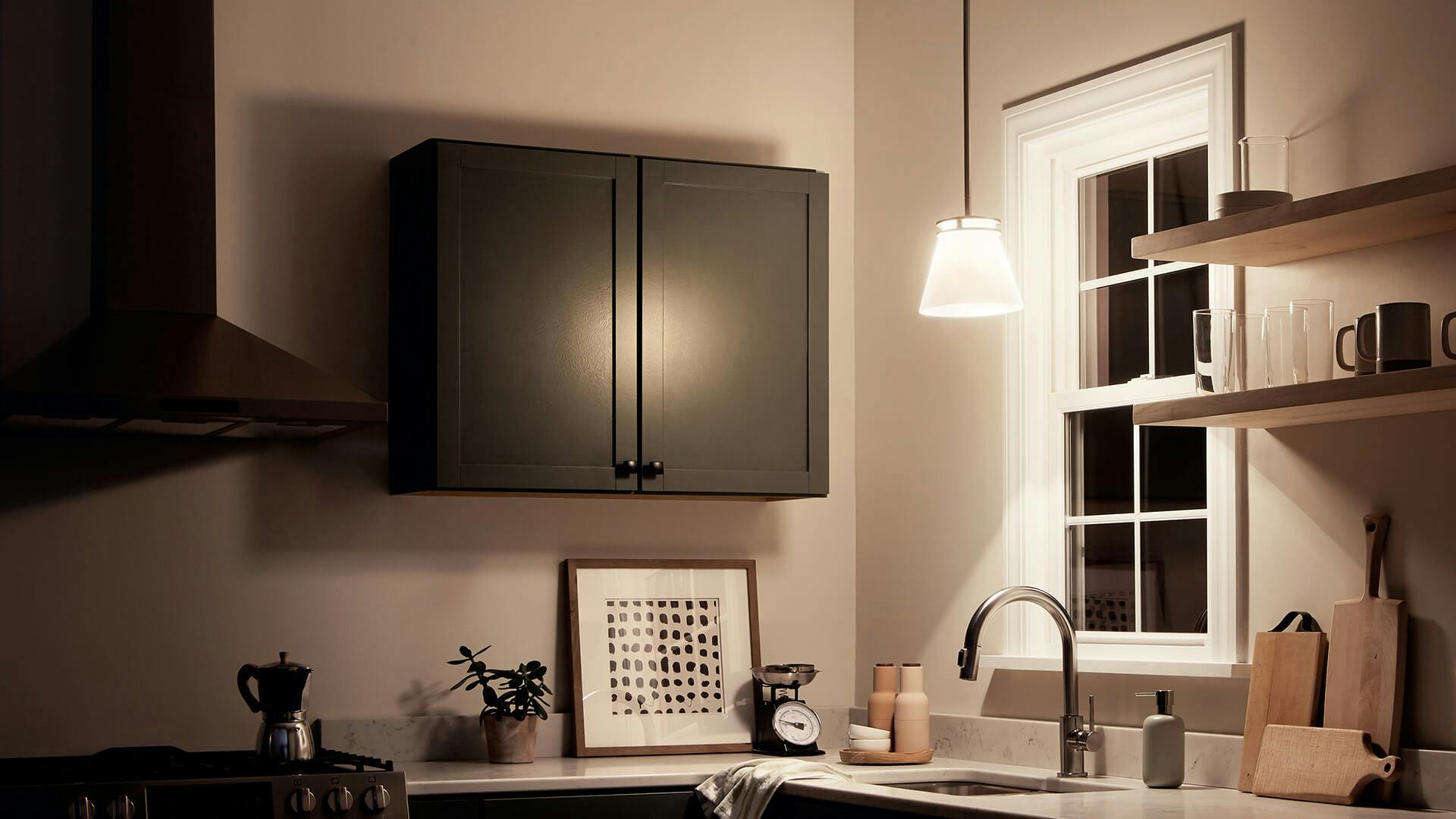Kitchen corner at nighttime with a single Hendrik pendant glowing above the sink in front of the window