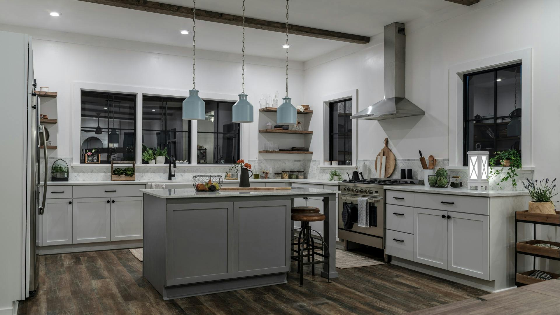 A kitchen with tape lights, shelf lighting, kicktoe lighting, and Montauk pendants, with just the downlights lights turned on at night