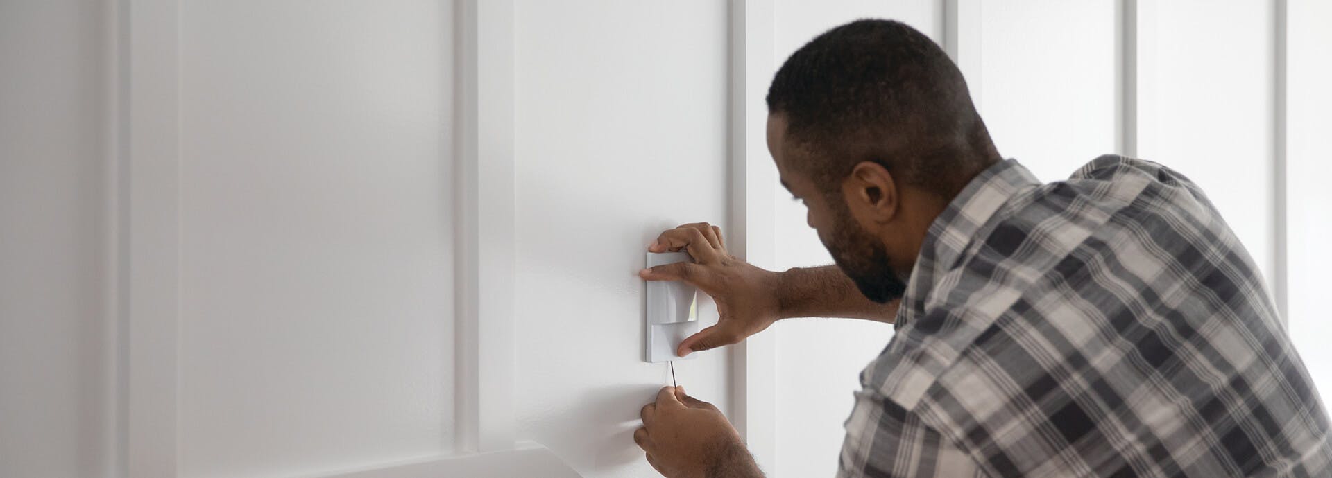 Man installing a dimmer light switch on a wall