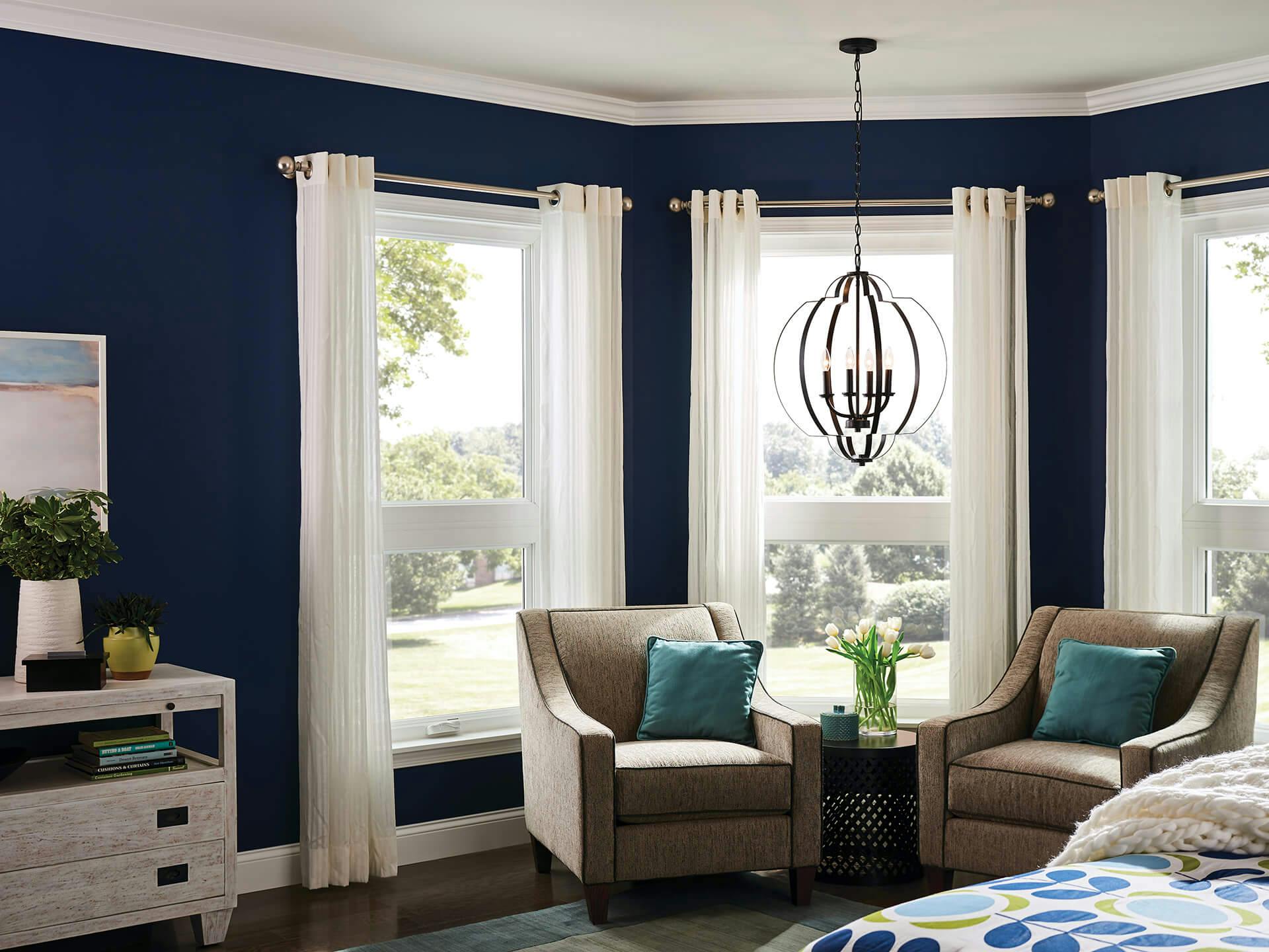 Bedroom with navy walls and three windows in the corner featuring a voleta pendant