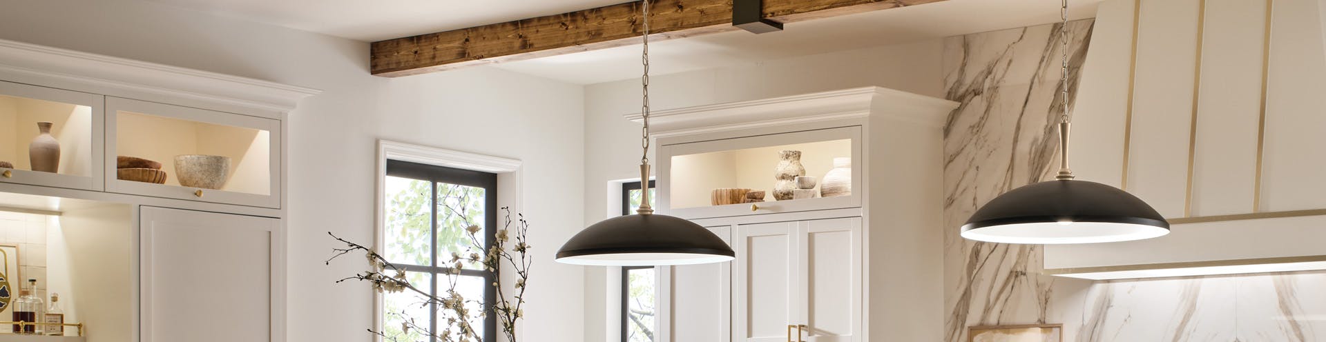 White kitchen with marble back splash, naural wood ceiling beams and two delarosa pendants in black
