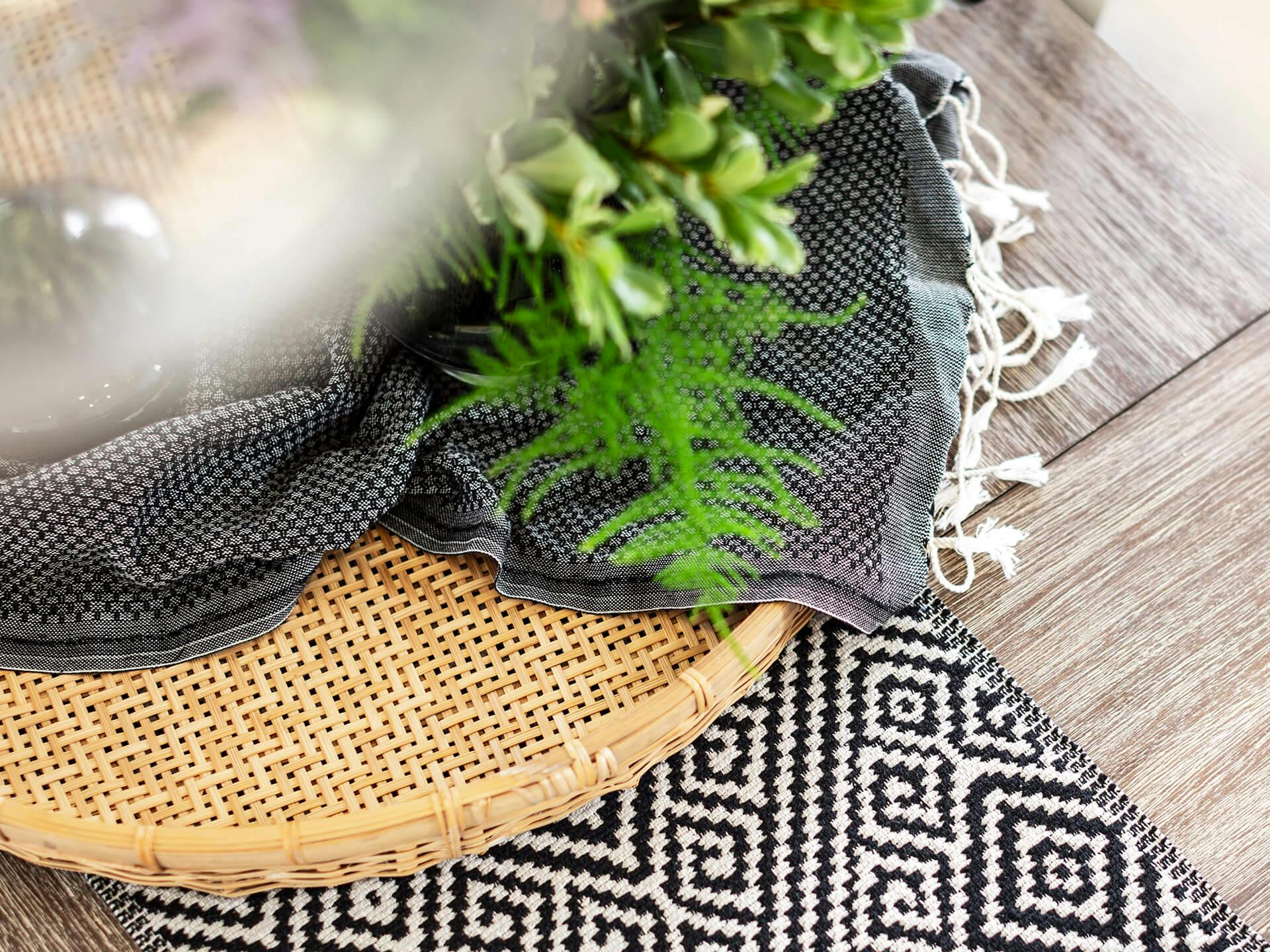 Close up of a woven tray with two different blankets and plants
