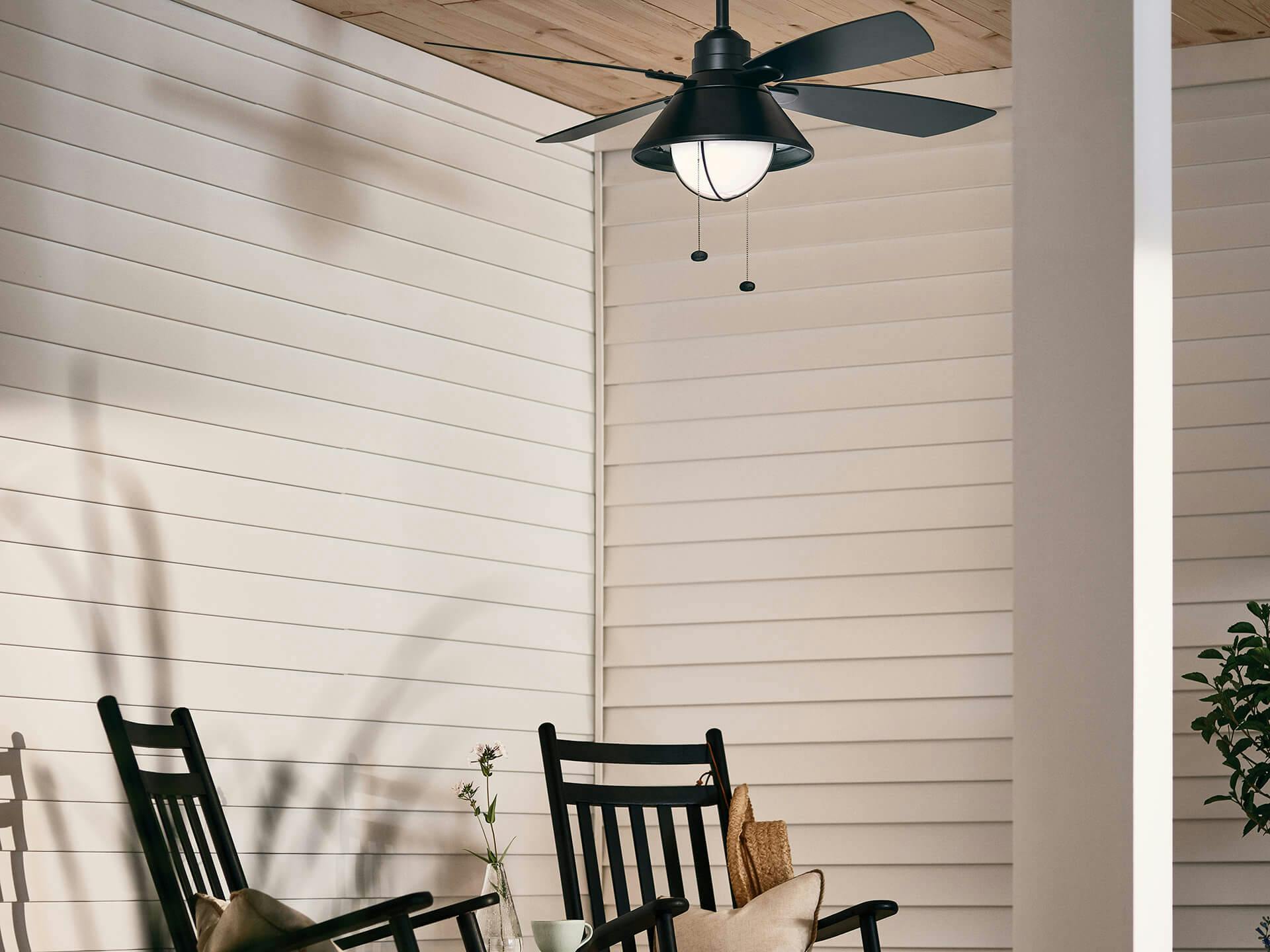 Outdoor porch with a seaside ceiling fan above two chairs