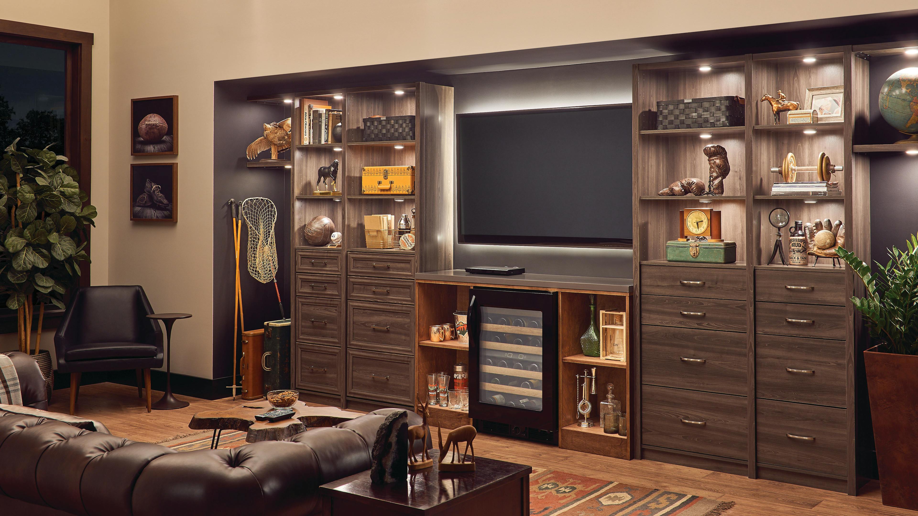 A living room or den with one inset wall lined with cabinet featuring cabinet lights within highlight various collectibles.