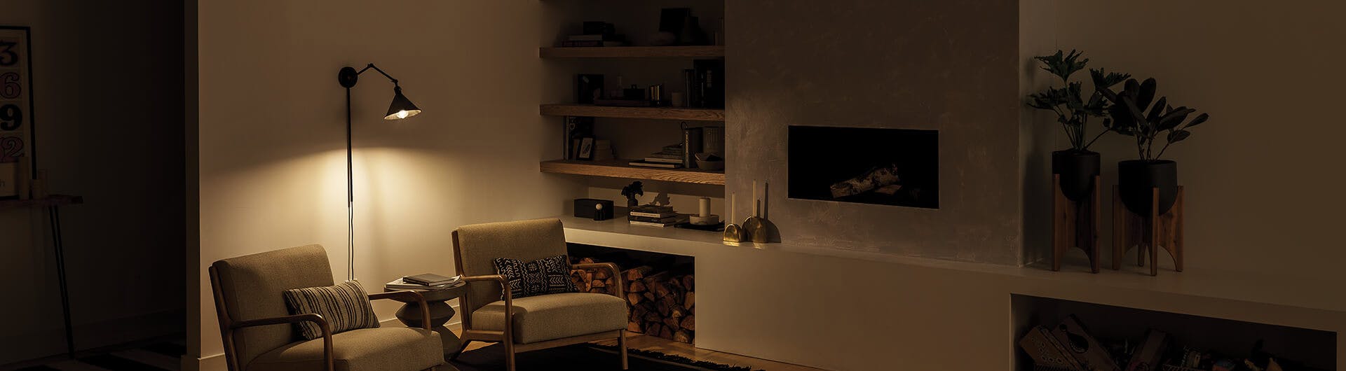 Reading nook lit with a Rosewood wall sconce and shelf lights at night 