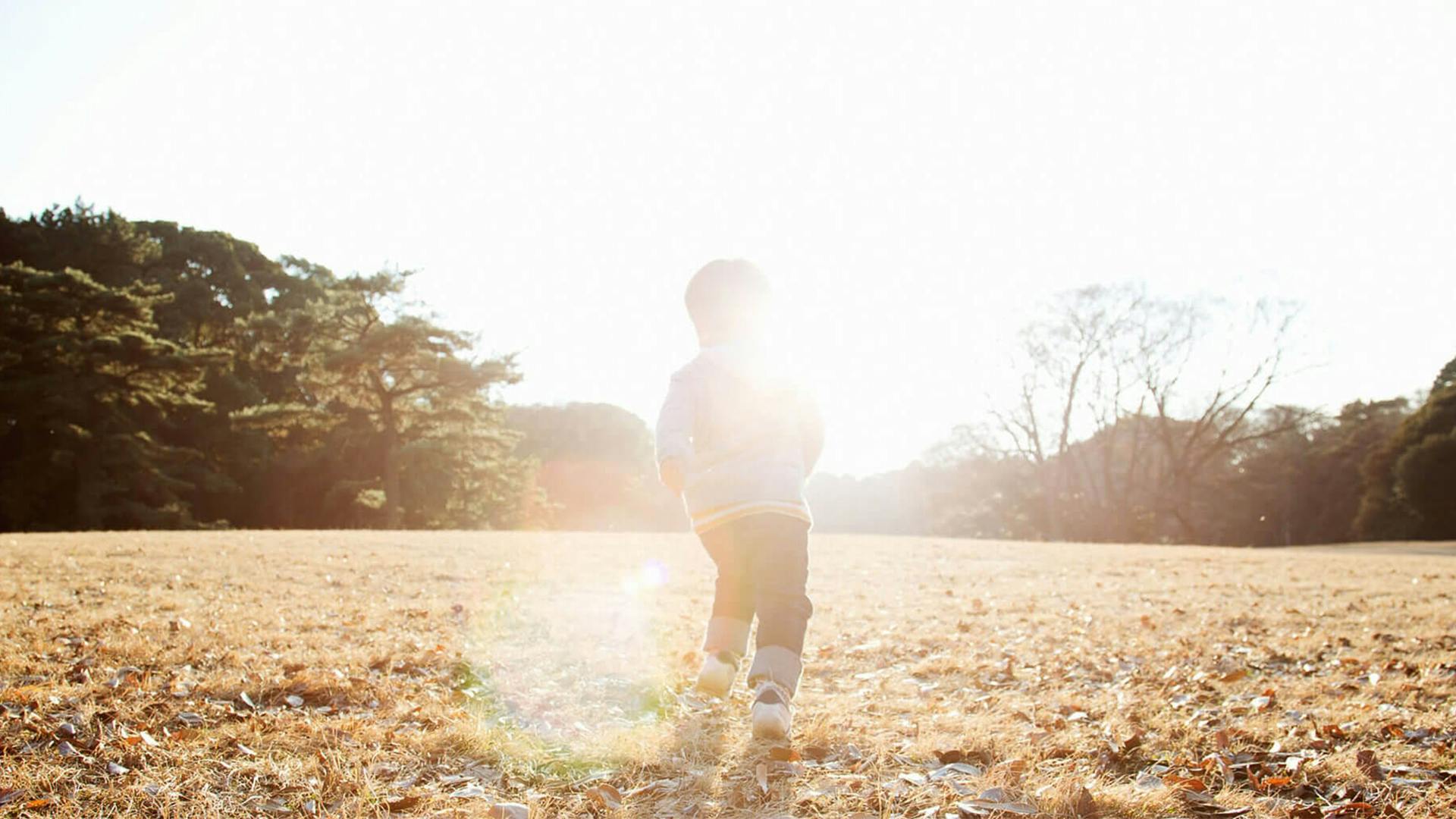A silhouette of a child lit with white light running through a field outside