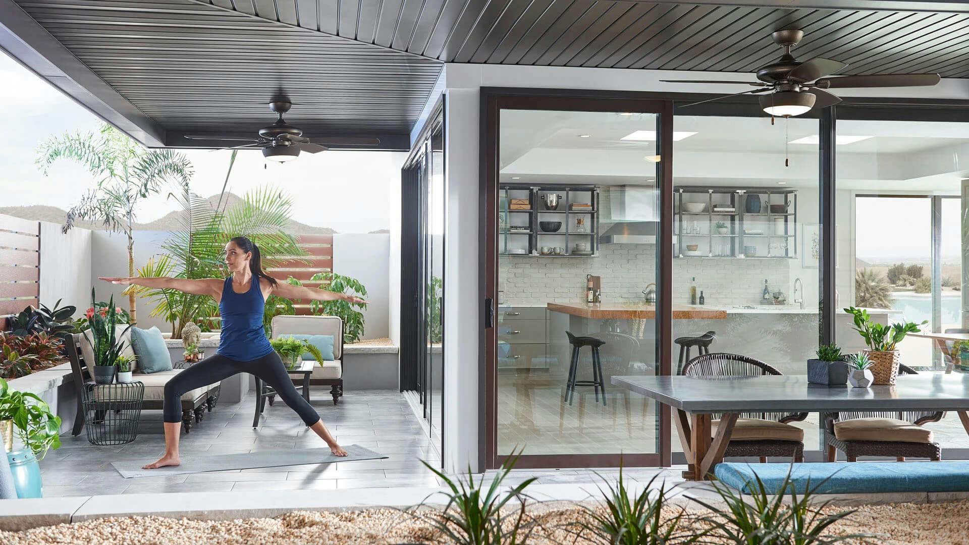 Outdoor patio with a woman doing yoga under a Kevlar ceiling fan with an attached light kit