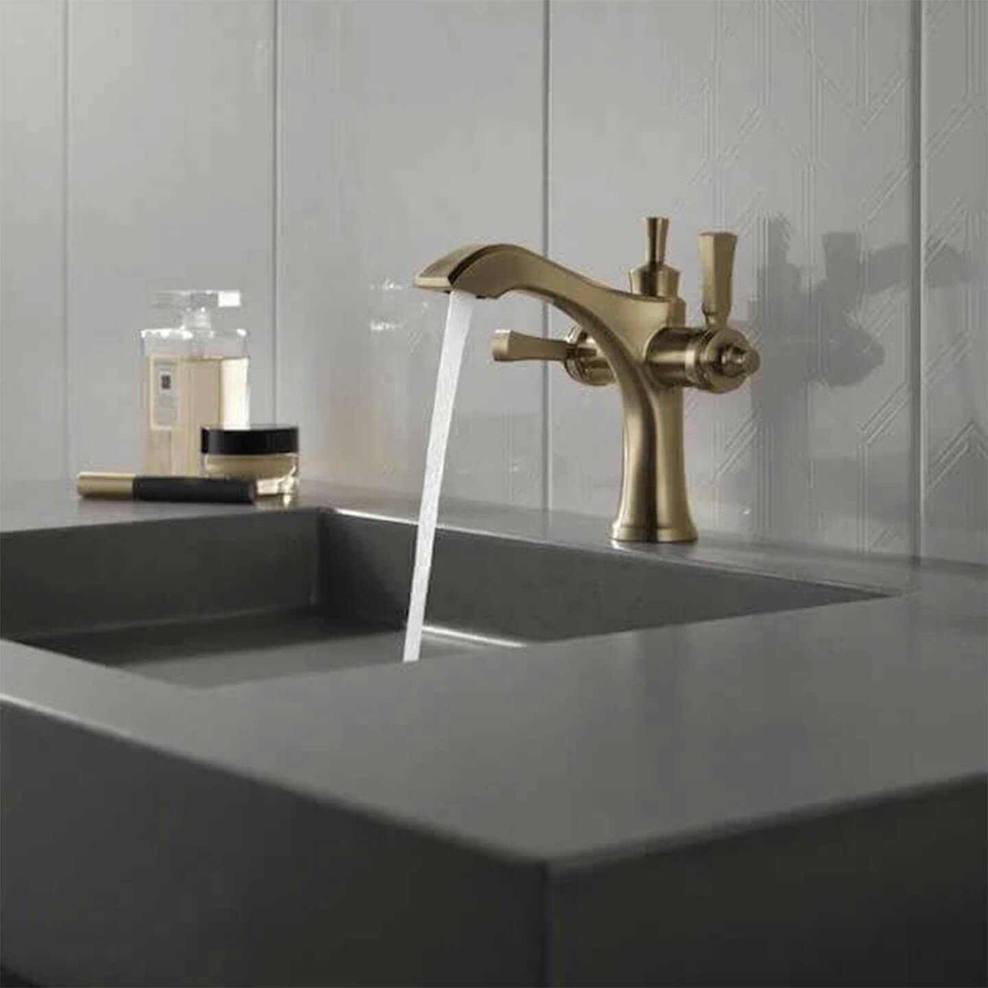 Champagne Bronze faucet with water running into a dark stone sink