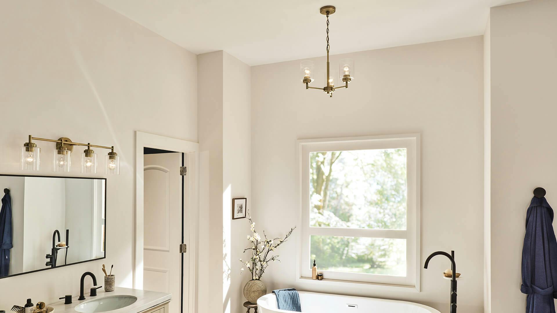White bathroom with Winslow 3-light pendant hanging above a white soaker tub in front of a window