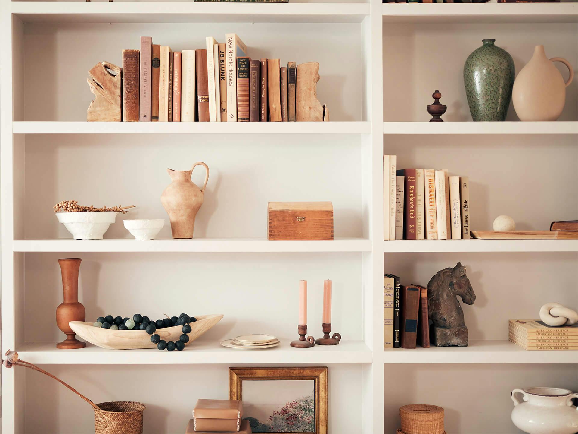 Bookshelf arranged with various books, vases, bowls, etc