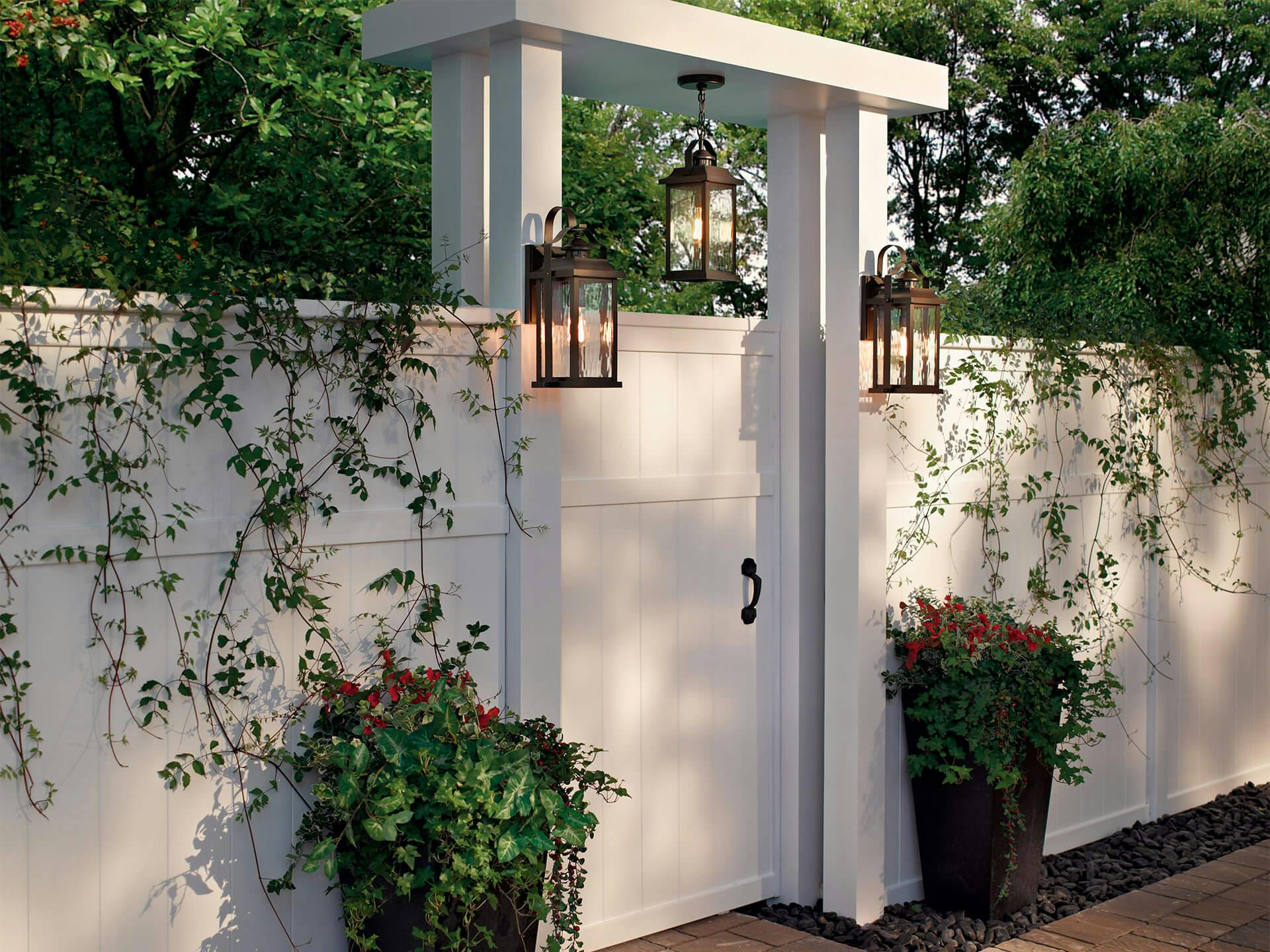Exterior image of a wooden garden wall entrance lit with Linford exterior wall and pendant lights during the day