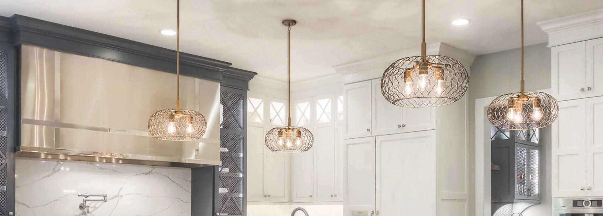 Four Devin pendant lights in gold finish hanging in a farmhouse style white kitchen
