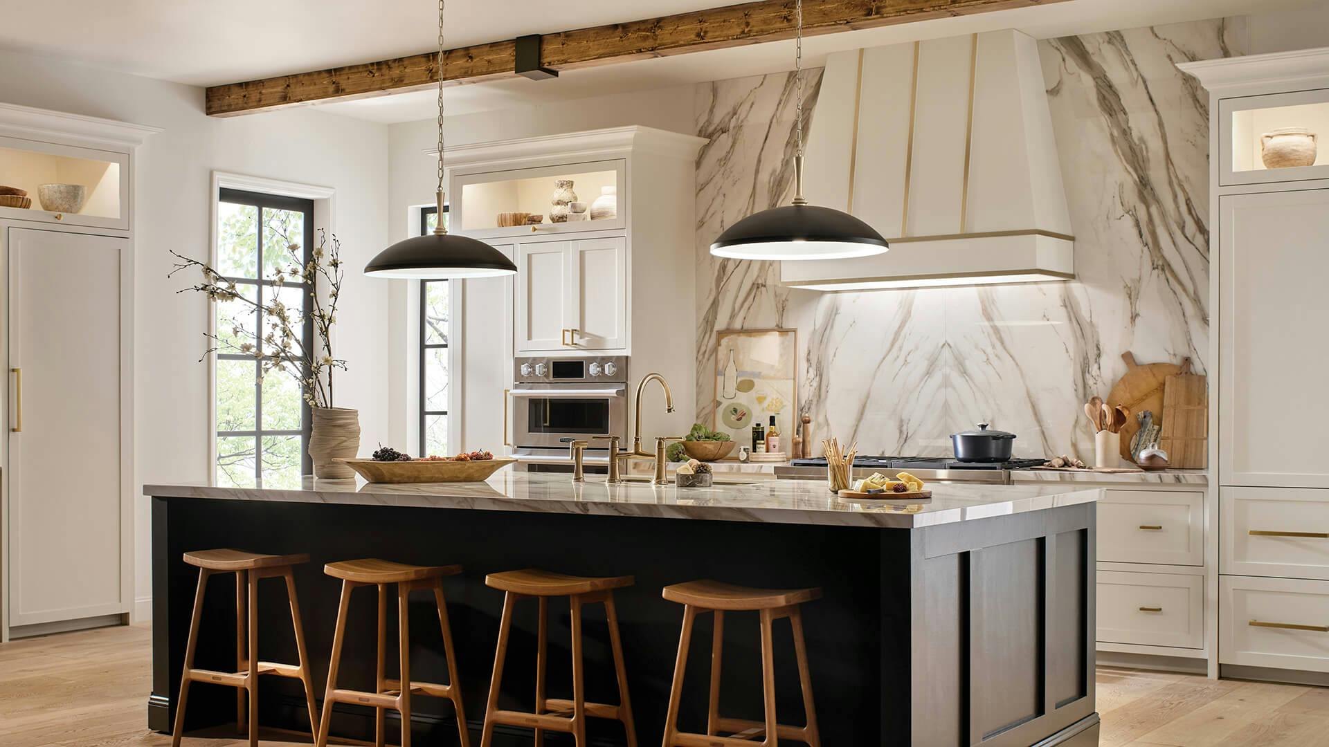 White and wood accented kitchen with black and gold finish Delarosa pendant lights above a large kitchen island