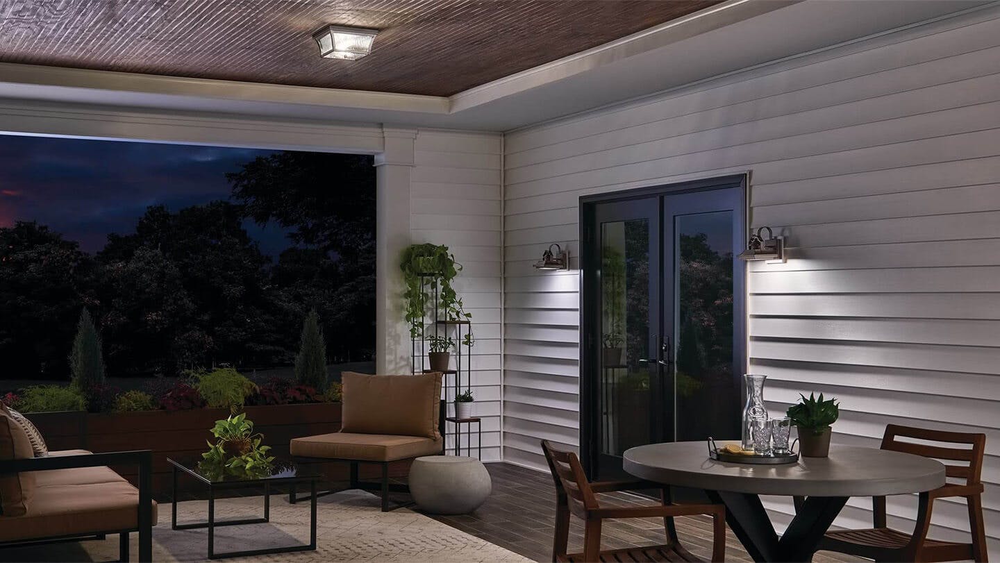 A covered back patio lit up with a Linford flush mount and Linfor exterior wall lights during the night 