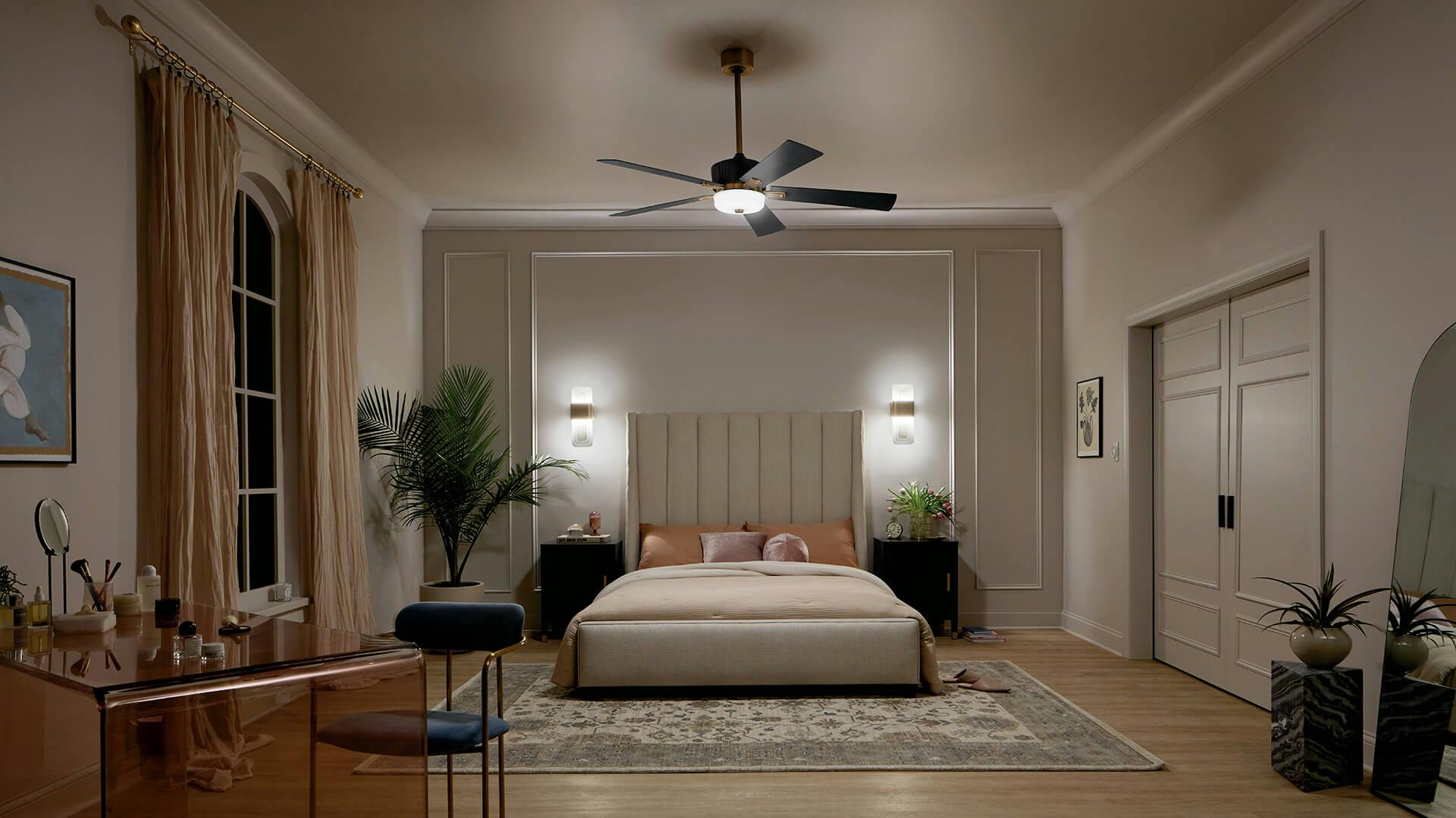 Expansive bedroom at night lit by two sconces on each side of the bed with a central Icon ceiling fan