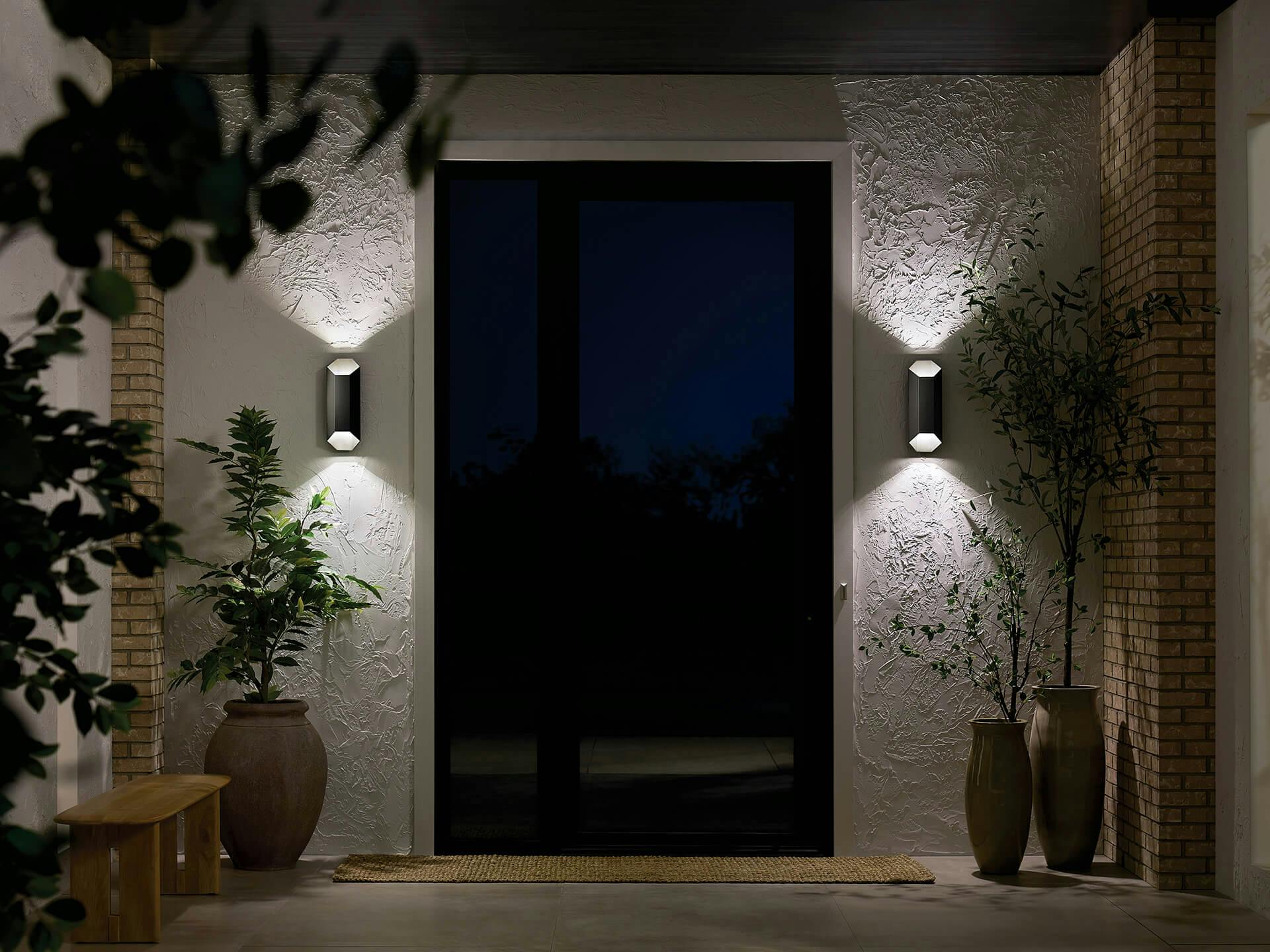 Two estella wall sconces on either side of a front door at night