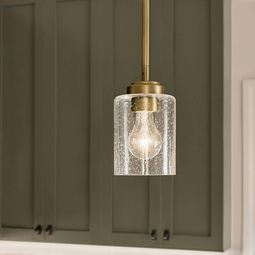 Kitchen in day light with the Winslow 7.5" 1-Light Mini Pendant Light with Clear Seeded Glass in Natural Brass