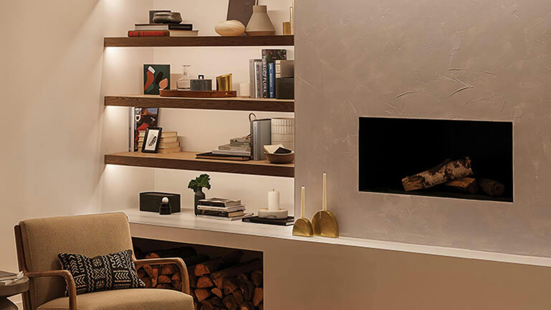 Tight shot of a fireplace beside an integrated bookshelf with channel lighting underneath the shelves
