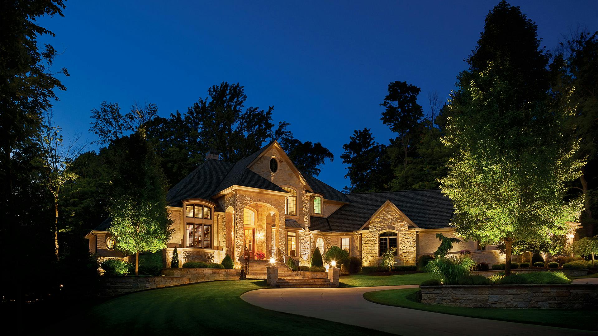 Outdoor night photo of a large home lit up by a variety of lights