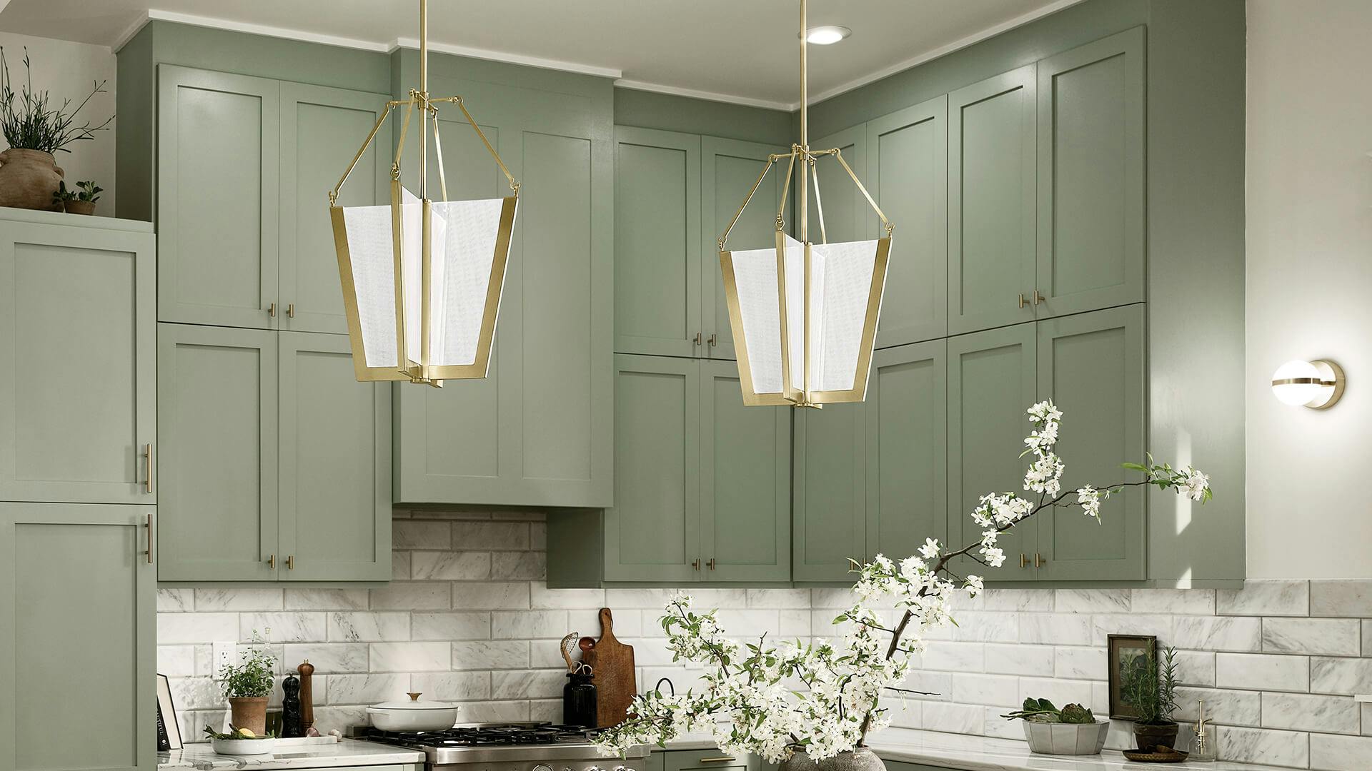 Kitchen with green cabinets featuring two gold finish Calter pendants