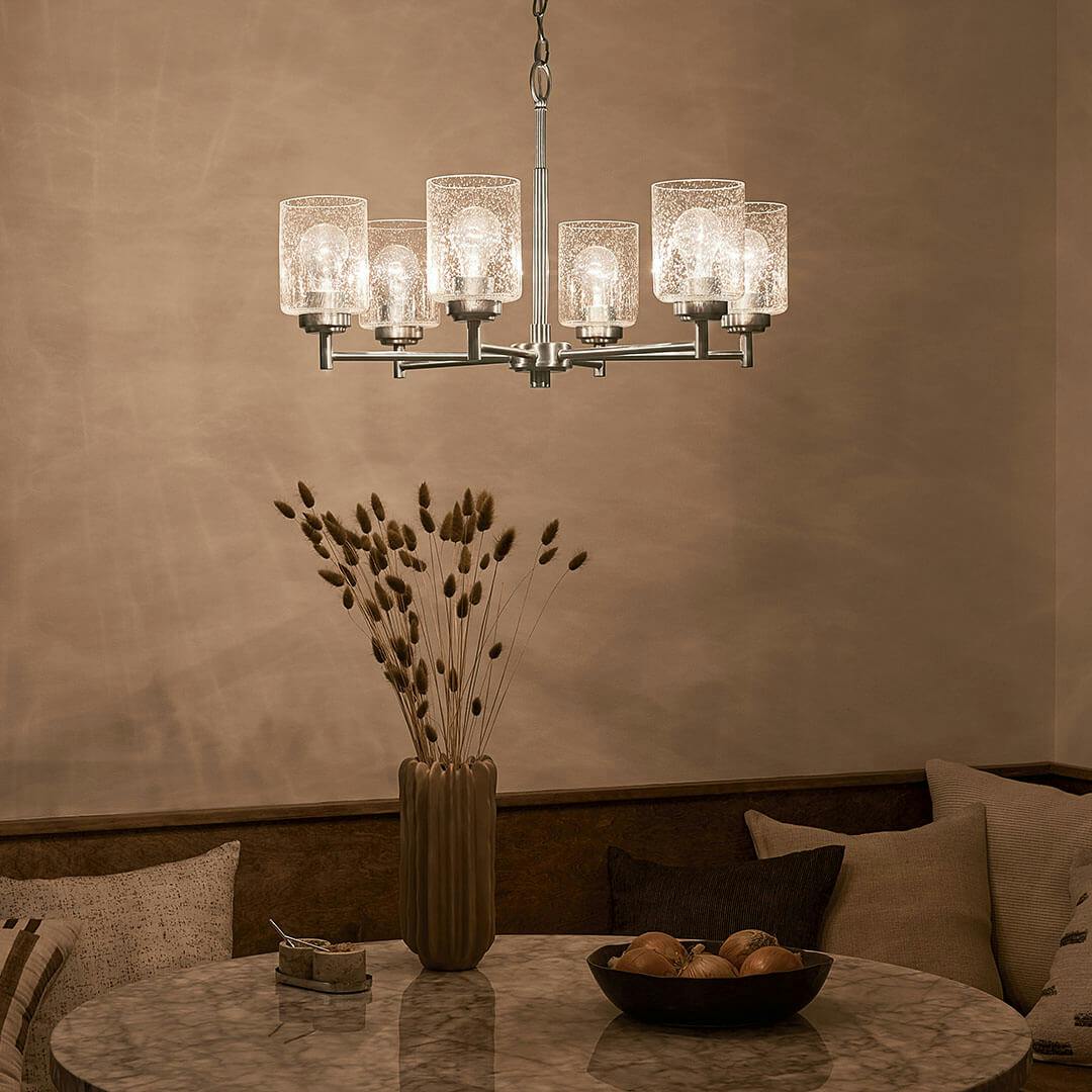 Dining room at night with the Winslow 26-Inch 6 Light Chandelier with Clear Seeded Glass in Brushed Nickel