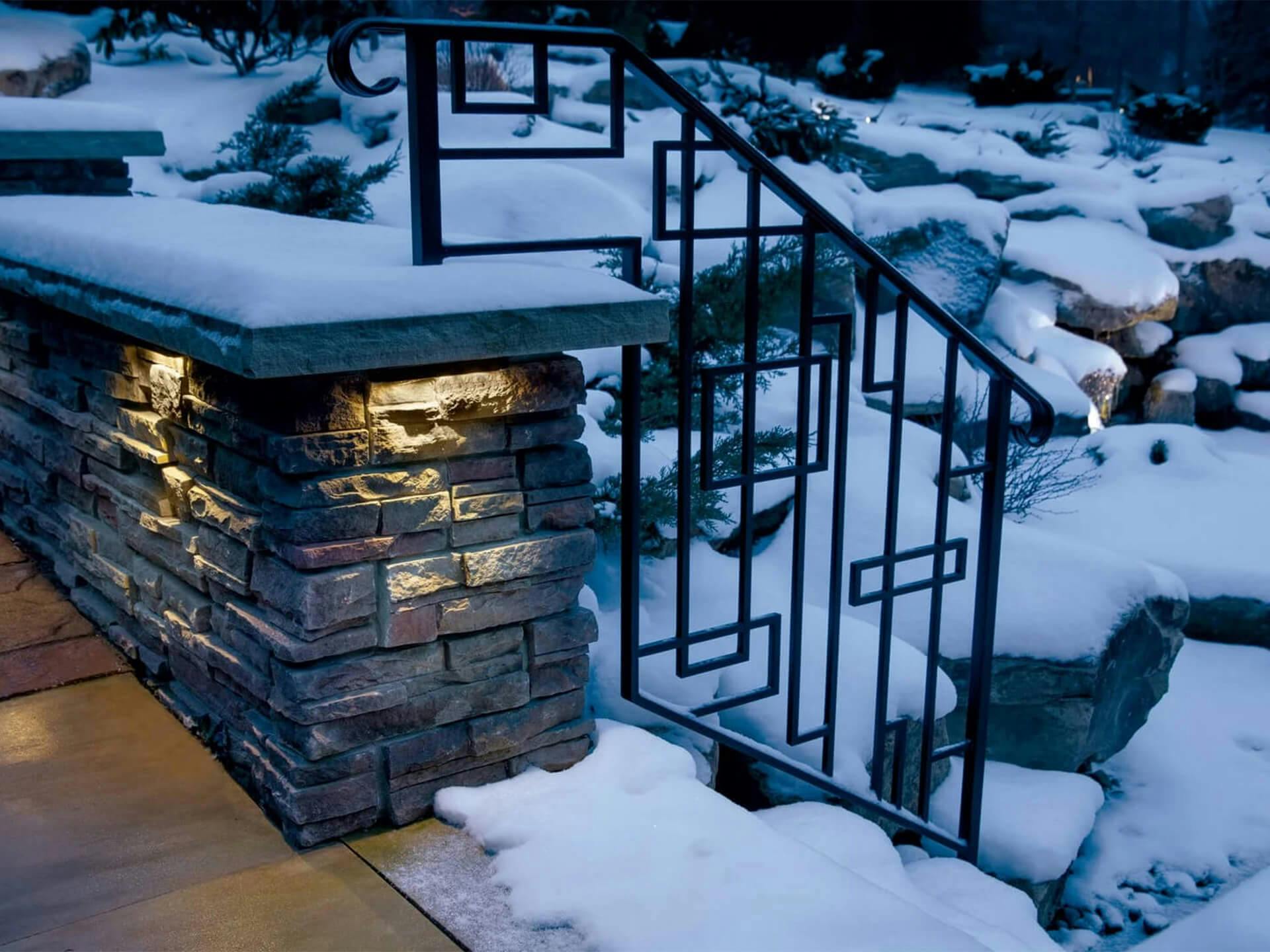 Snowy back yard focusing on patio stairs with downlights