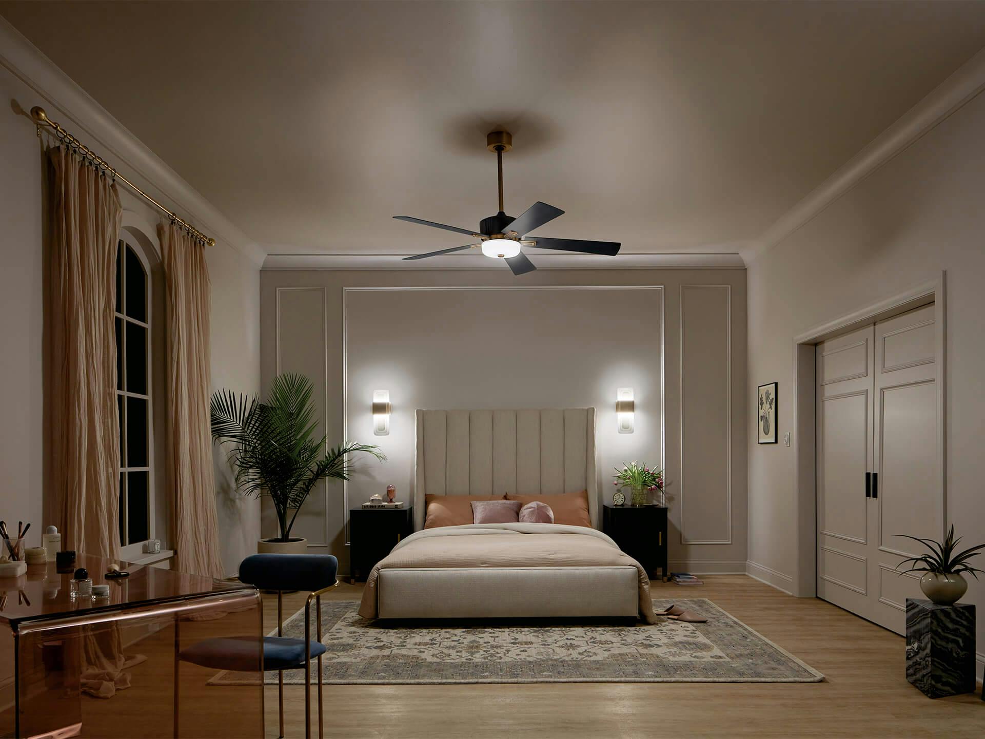 Bedroom at night with an icon ceiling fan in the center with sconces on either side of the bed frame.