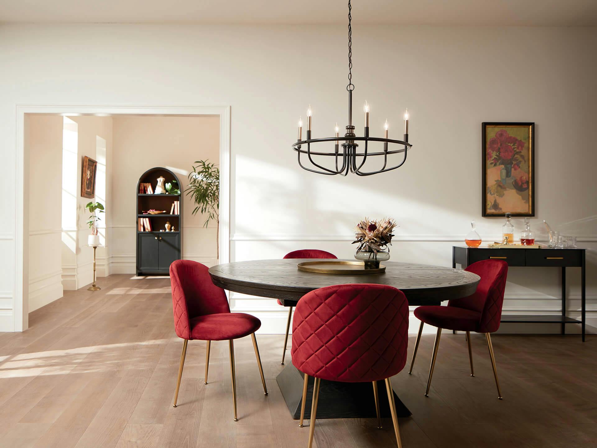 Dining room during the day with red chairs around a circular table featuring a Capitol Hill chandelier in black finish