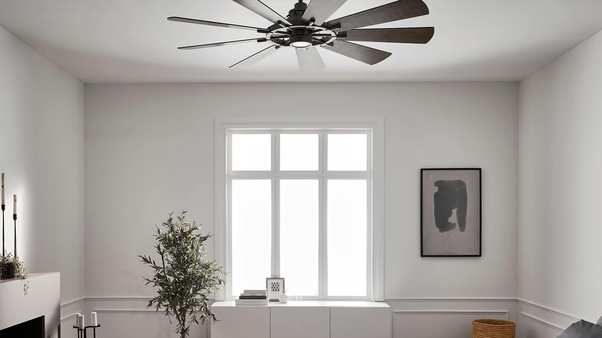 Sun shines through a central window of a white bedroom with a Gentry ceiling fan mounted above