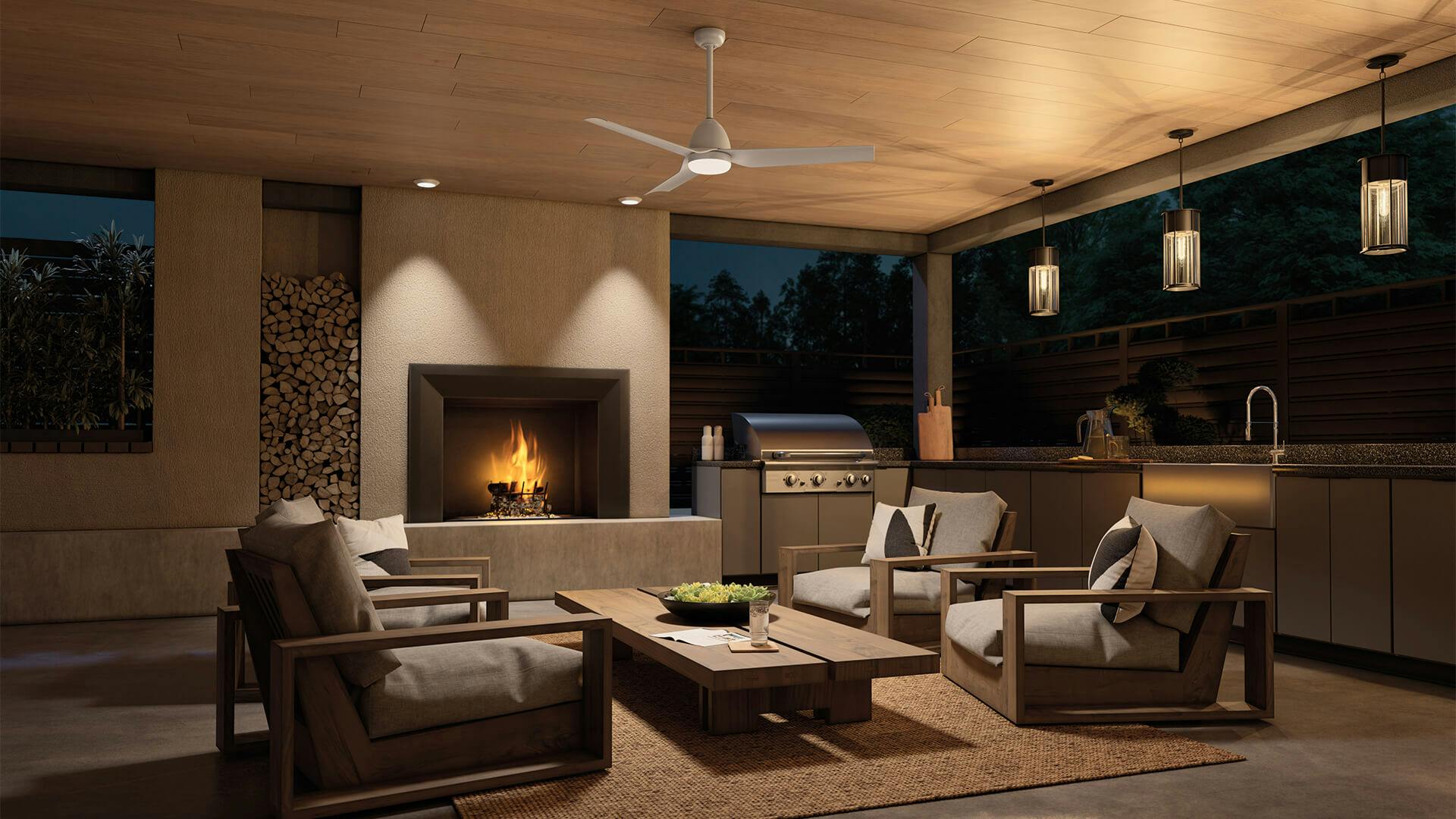Covered patio with fireplace and kitchen and Fit fan in white finish at night