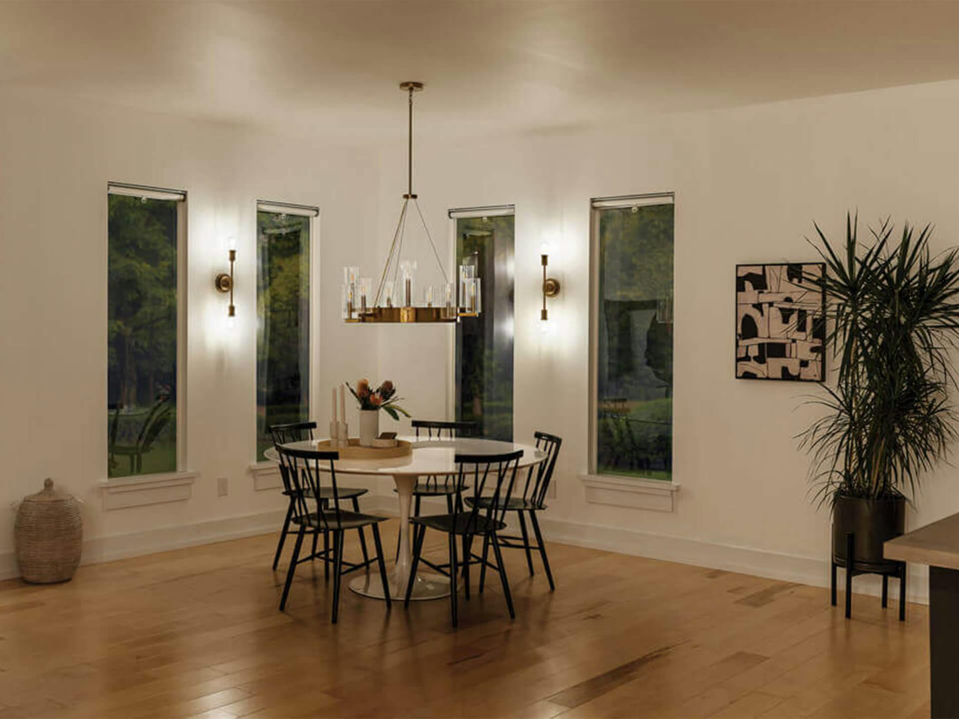 A dinning room lit with two Armstrong sconces and a Cleara Chandelier turned off above a dinning table at night 